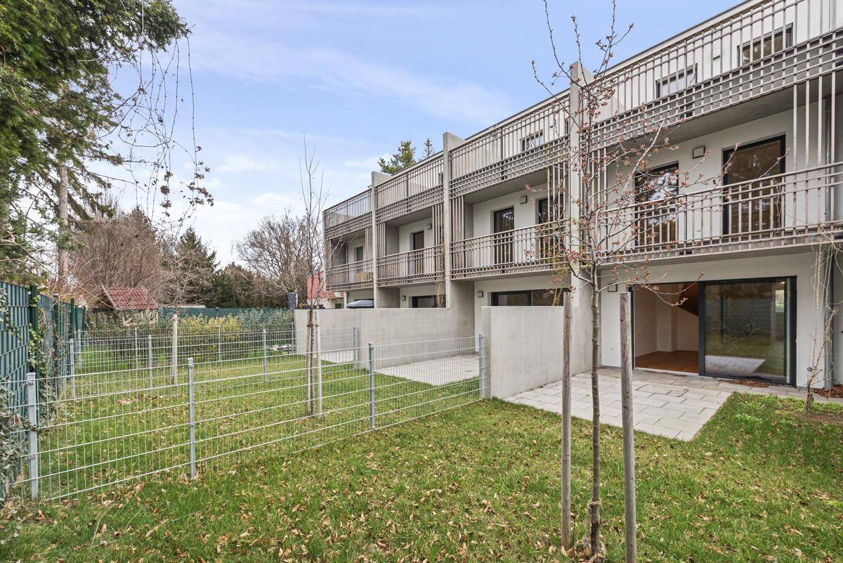 Rückseite der Reihenhäuser mit privaten Gärten und Balkonen im Obergeschoss.