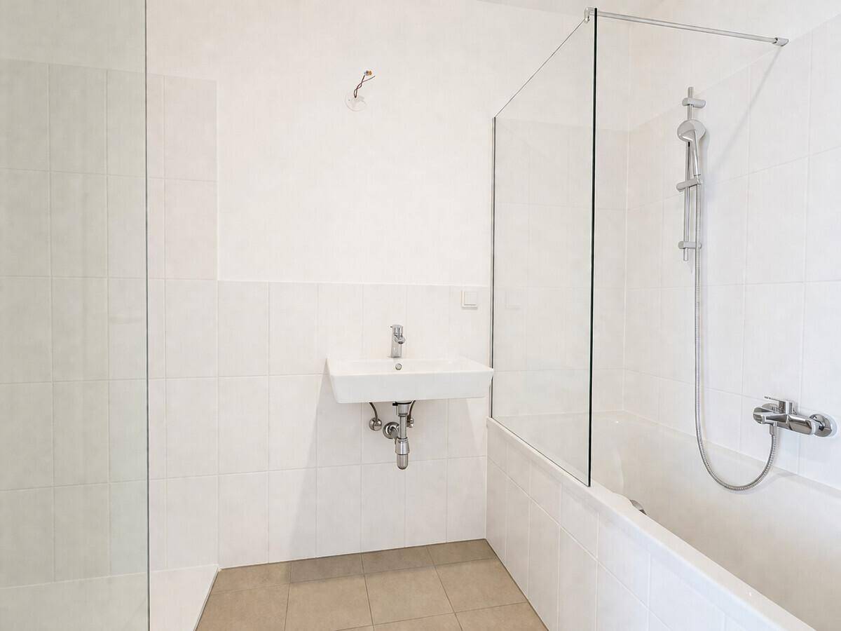 Modernes Badezimmer mit Badewanne, Dusche und weißen Fliesen an den Wänden.