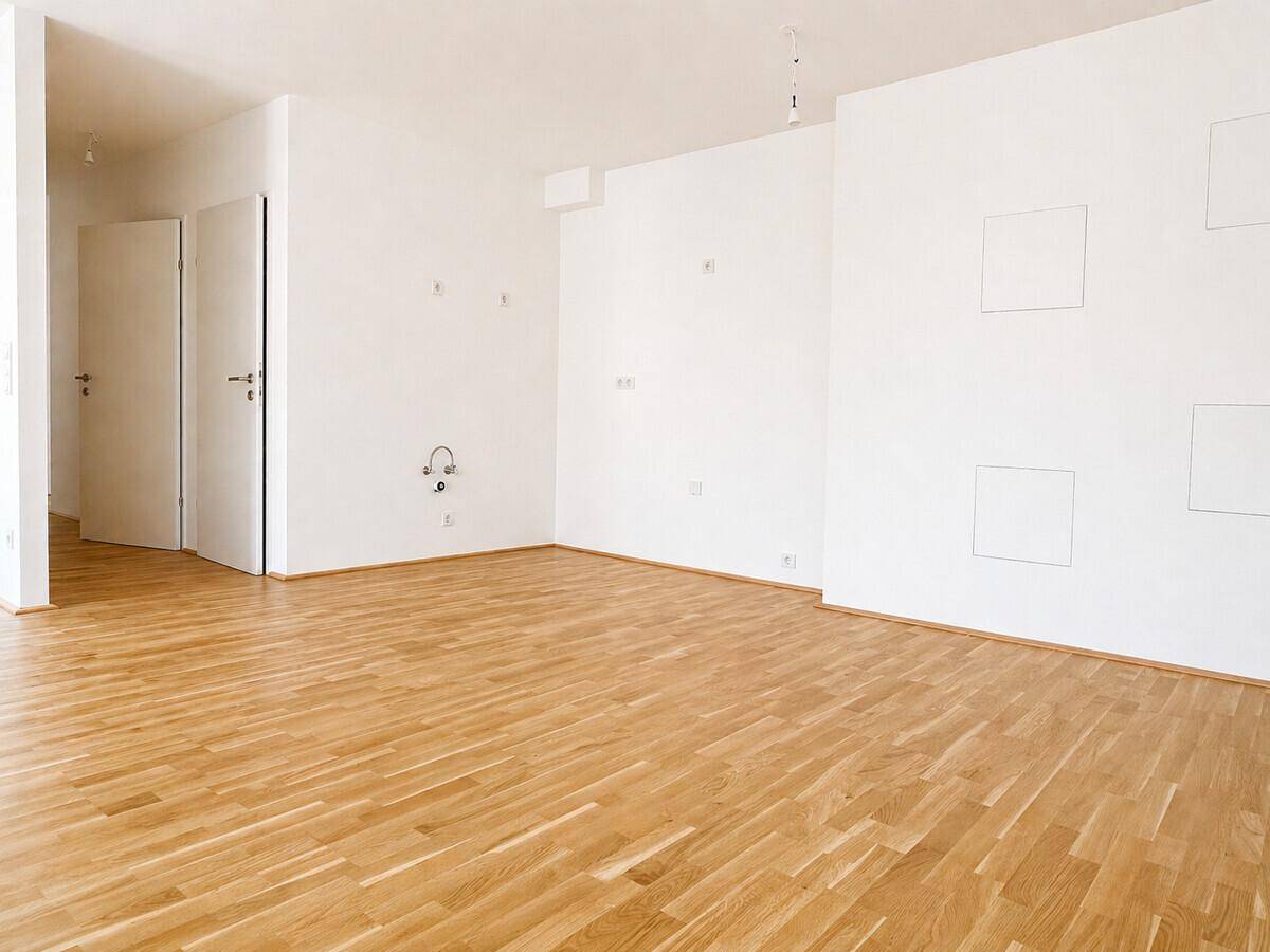 Unmöbliertes Zimmer mit hellem Parkettboden und weißen Wänden, bereit zum Einzug.