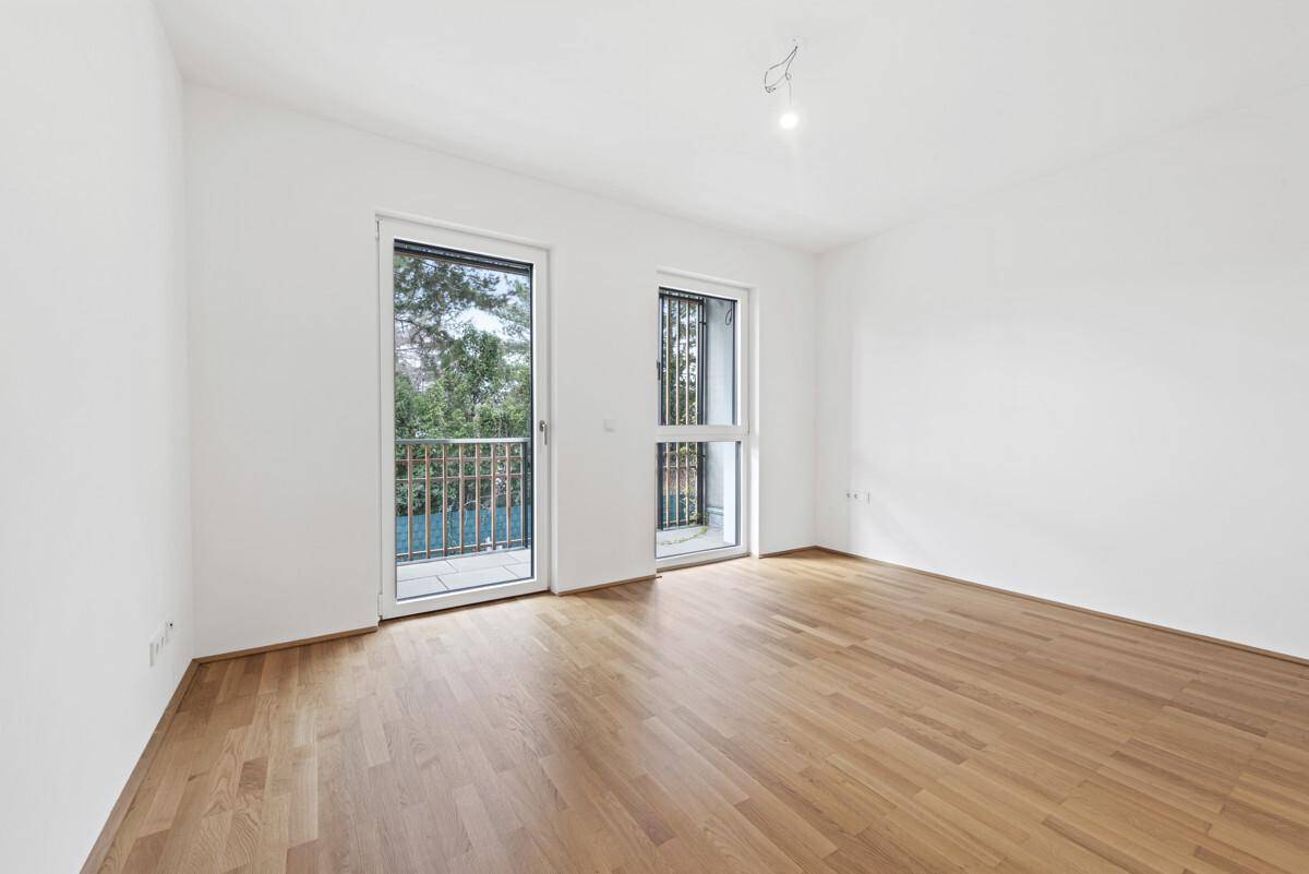 Helles Schlafzimmer mit Parkettboden und zwei Fenstertüren zum französischen Balkon.