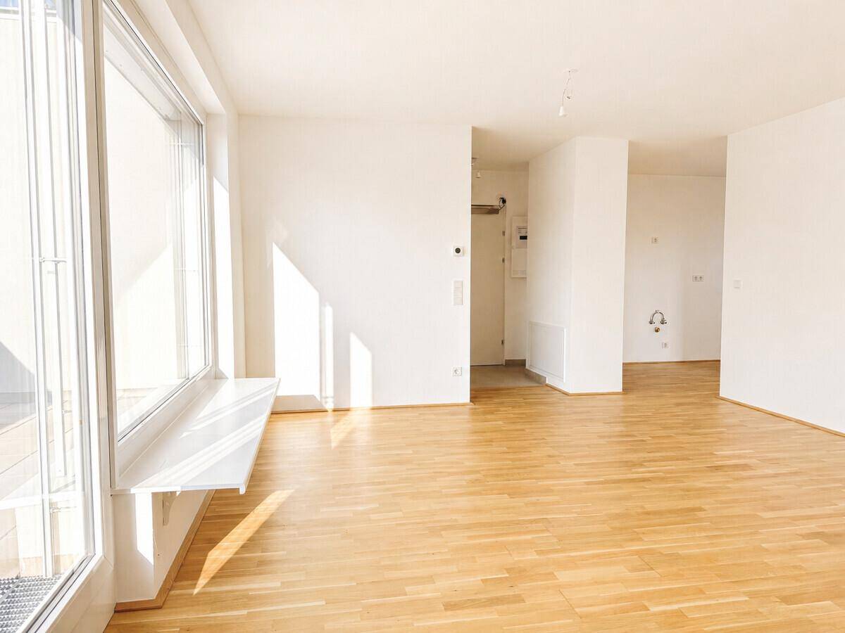 Lichtdurchfluteter Wohnraum mit Parkettboden und großzügigen Fensterfronten zur Terrasse.