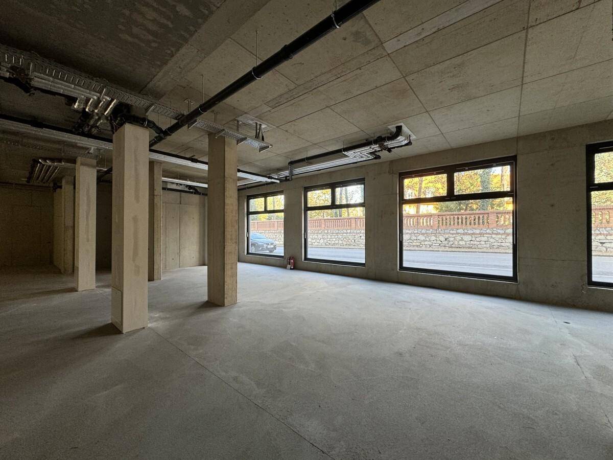Unfertiger Gewerberaum mit Betonboden, großen Fenstern und sichtbaren Deckeninstallationen, bereit für den Ausbau.