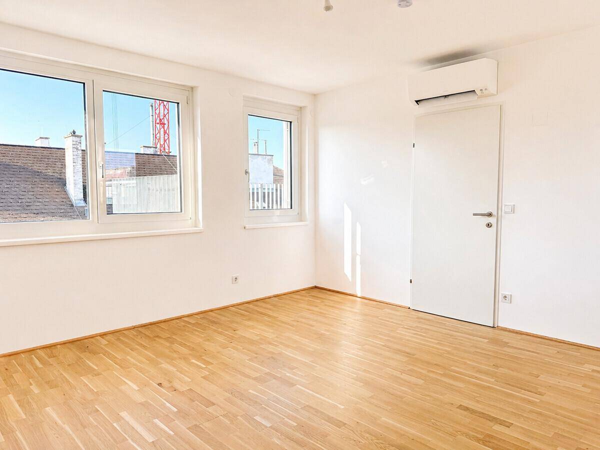 Helles Schlafzimmer mit Parkettboden, Klimaanlage und Fenstern mit Ausblick.