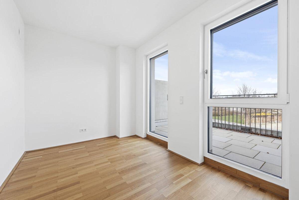 Lichtdurchflutetes Zimmer mit Holzparkett und Zugang zu einem weiteren Balkon.