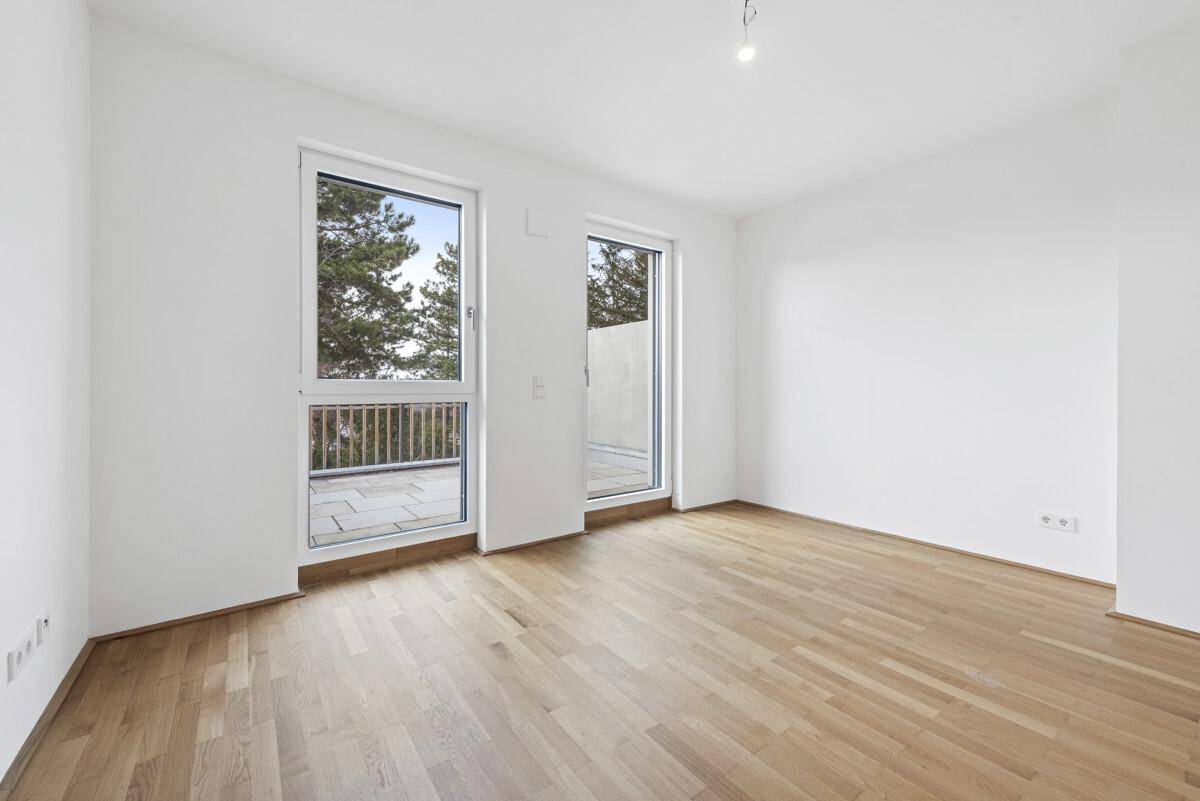Helles Zimmer mit großen Fenstern und direktem Zugang zum Balkon.
