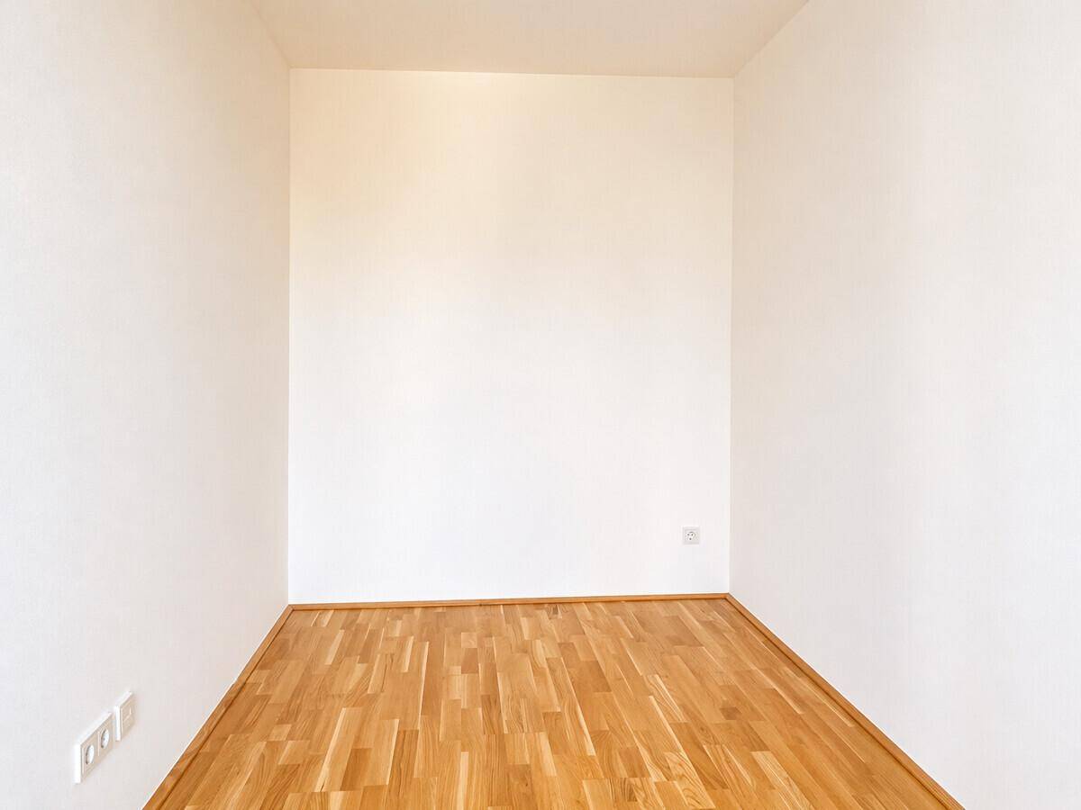Leerer Raum mit Parkettboden und weißen Wänden, ideal für individuelle Gestaltung.