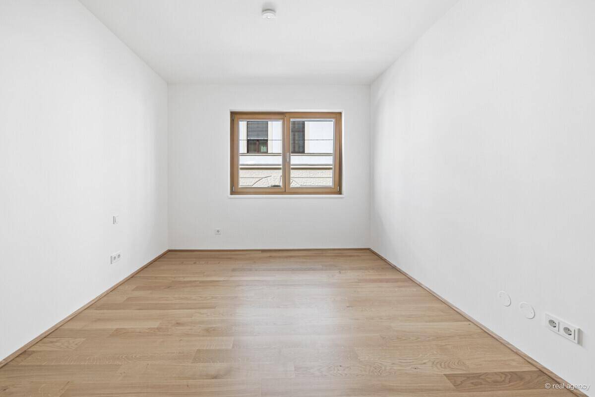 Ruhiges, helles Schlafzimmer mit Holzboden und einem Fenster für natürliche Belichtung.