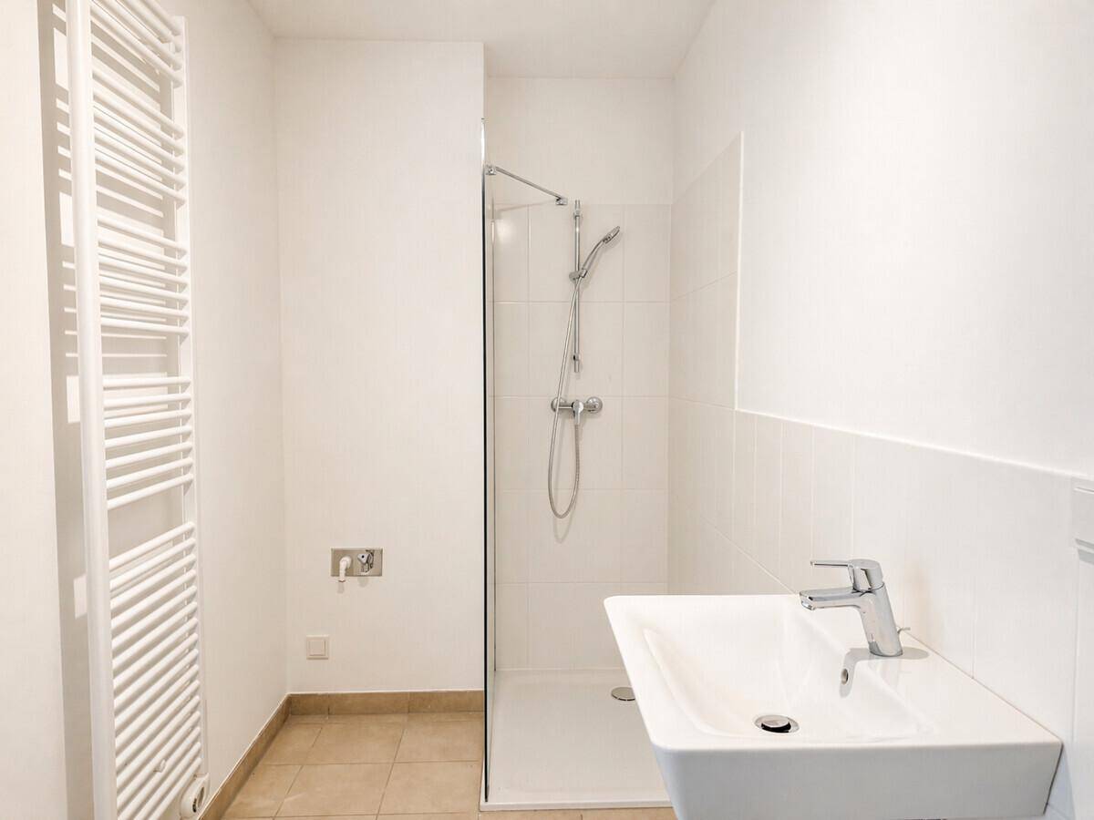 Modernes Badezimmer mit Dusche, Waschbecken und beheiztem Handtuchhalter in Weiß.