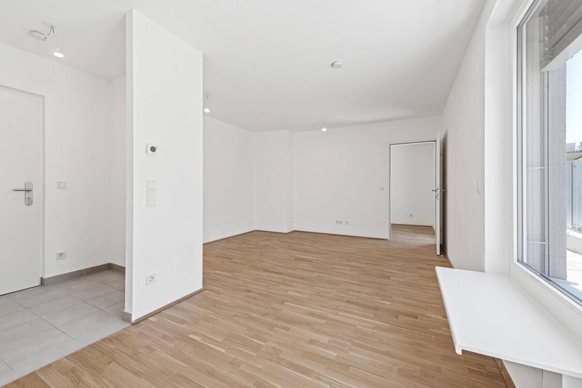 Geräumiger, heller Raum mit Holzboden und gefliestem Eingangsbereich, bereit zum Einrichten.