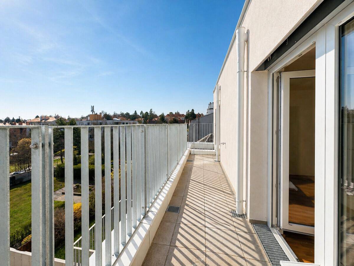 Langer Balkon mit Fliesenboden und Metallgeländer, der einen weiten Blick über die Stadt bietet.
