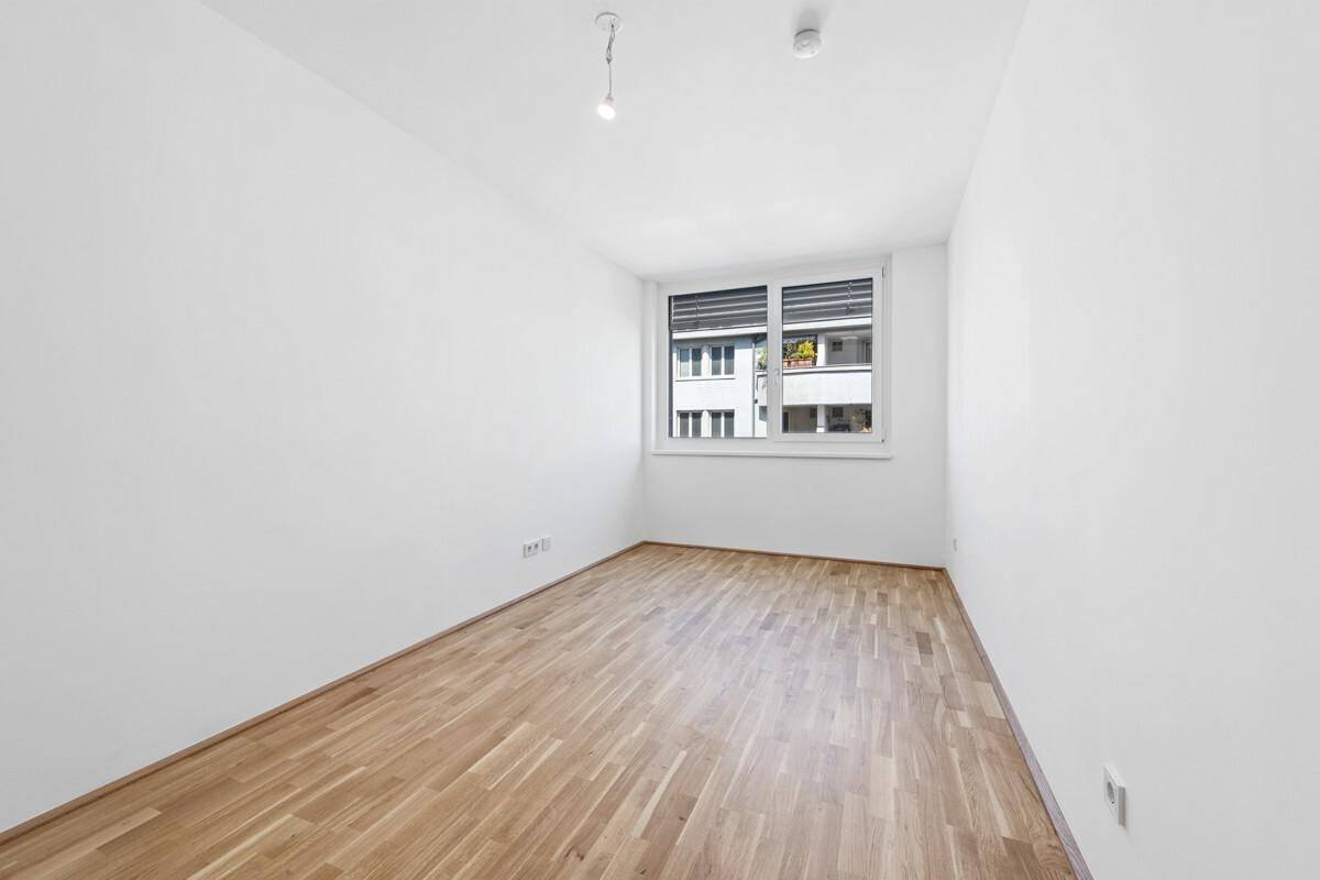 Kleineres Zimmer mit Parkettboden und Fenster, gut geeignet als Kinder- oder Gästezimmer mit Rollläden.