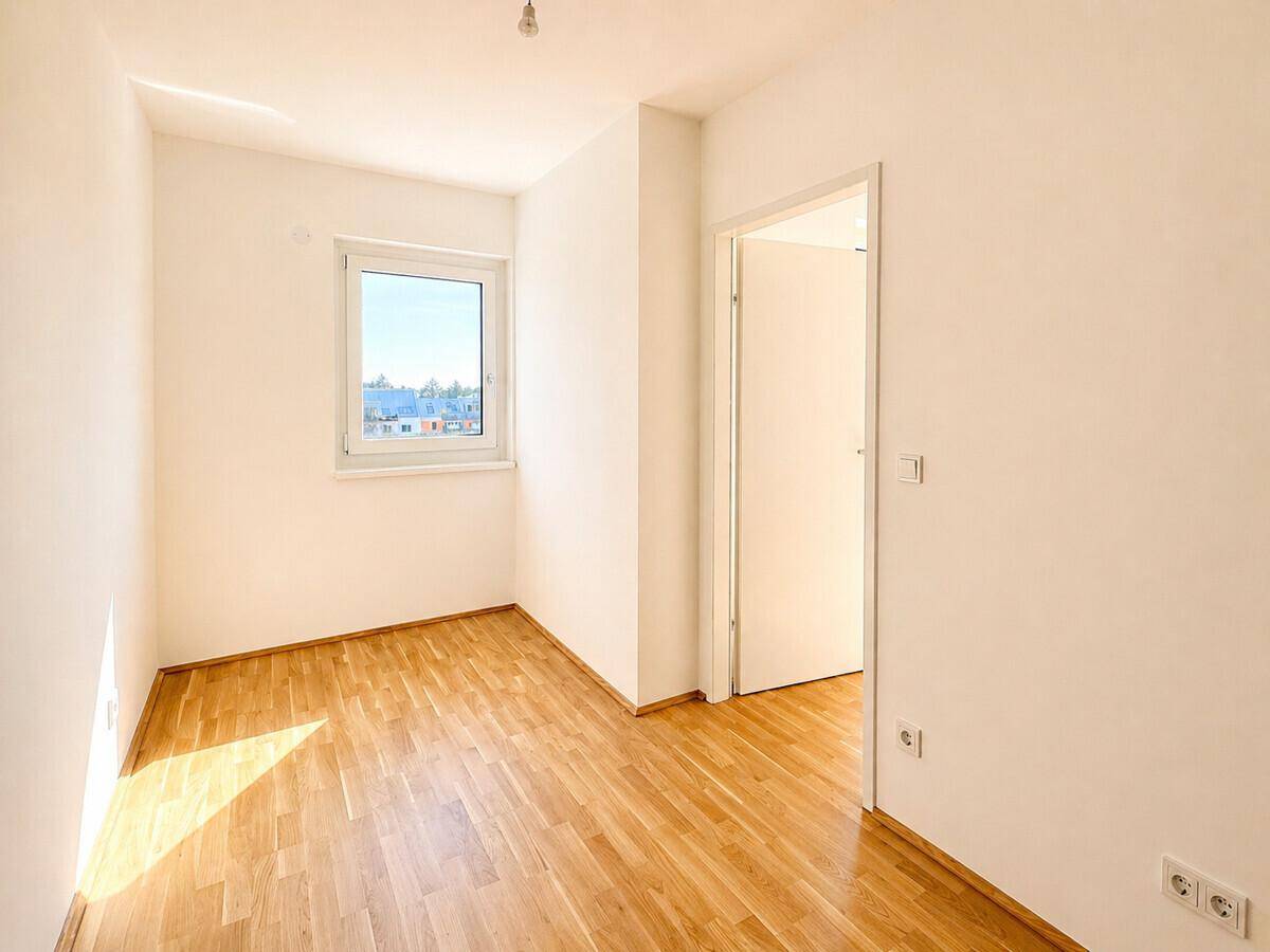 Kleiner, heller Raum mit Parkettboden und einem Fenster, ideal als Schlaf- oder Arbeitszimmer.