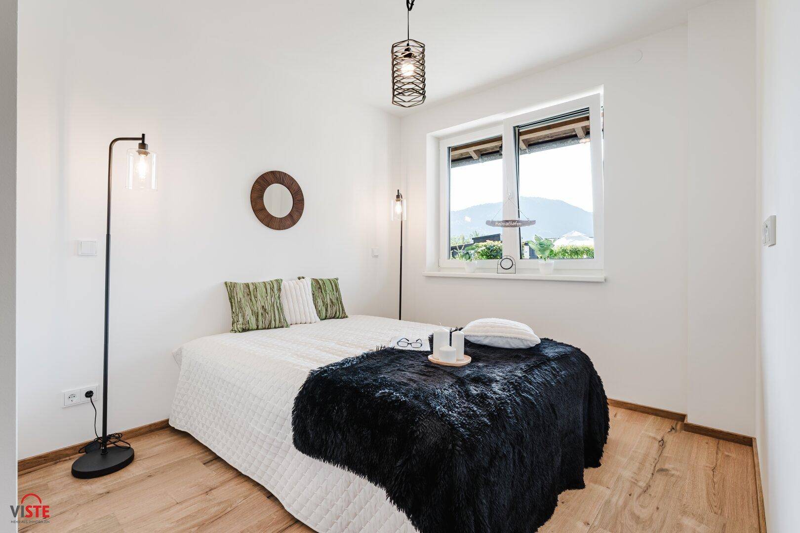 Gemütliches Schlafzimmer mit Doppelbett, Holzboden und Fenster mit Bergblick.