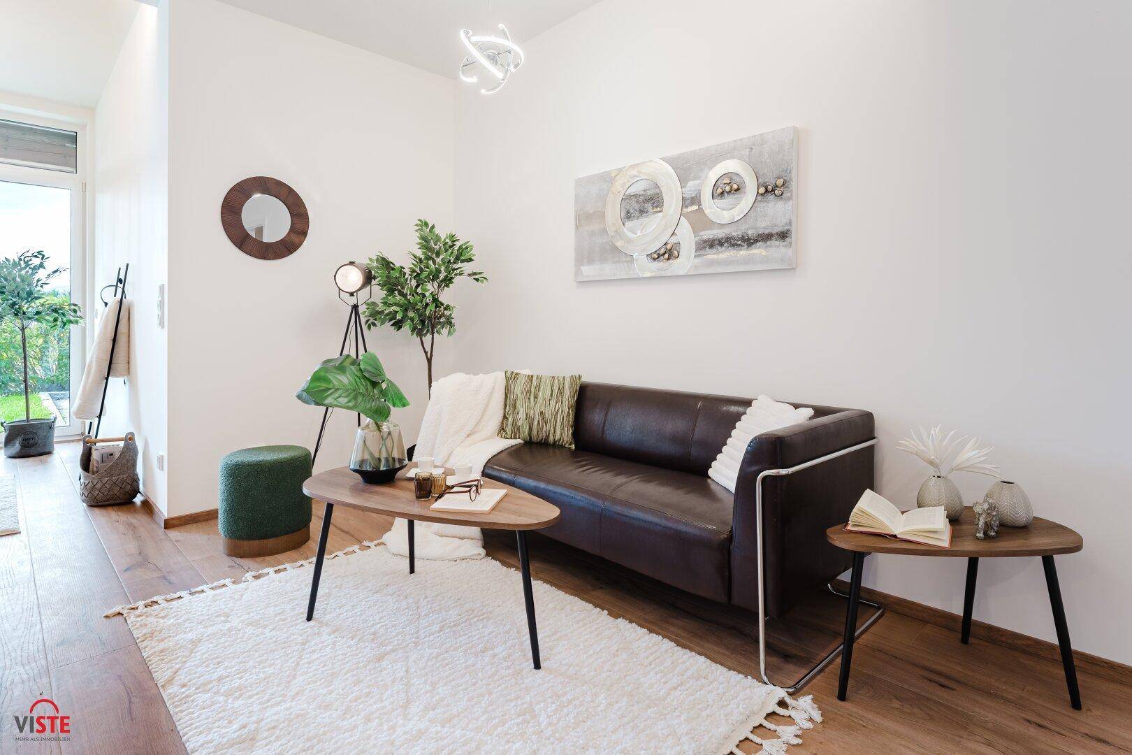 Gemütlicher Wohnbereich mit braunem Sofa, Holzboden und moderner Dekoration.