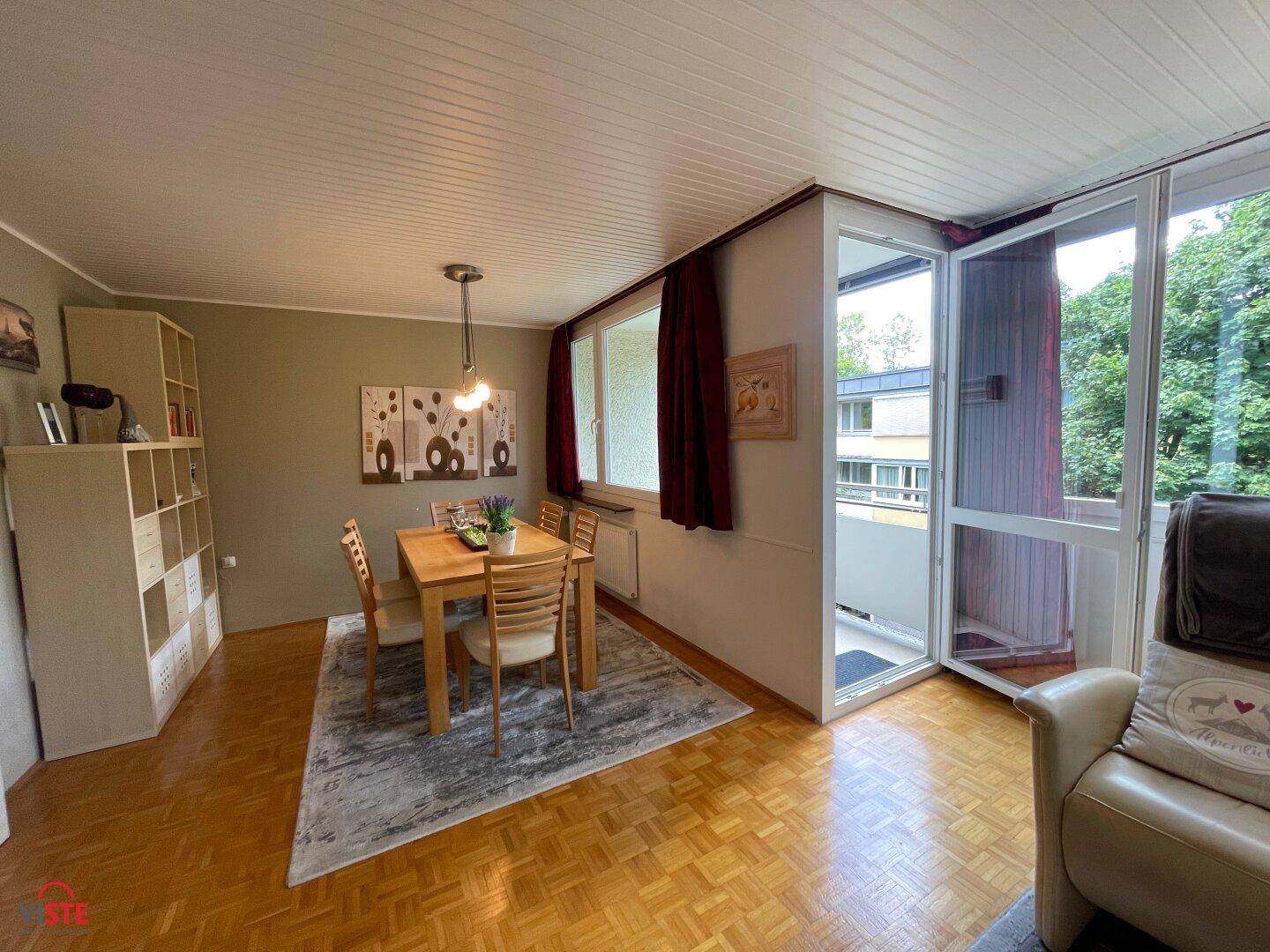 Heller Essbereich mit Holztisch, Parkettboden und direktem Zugang zum Balkon.