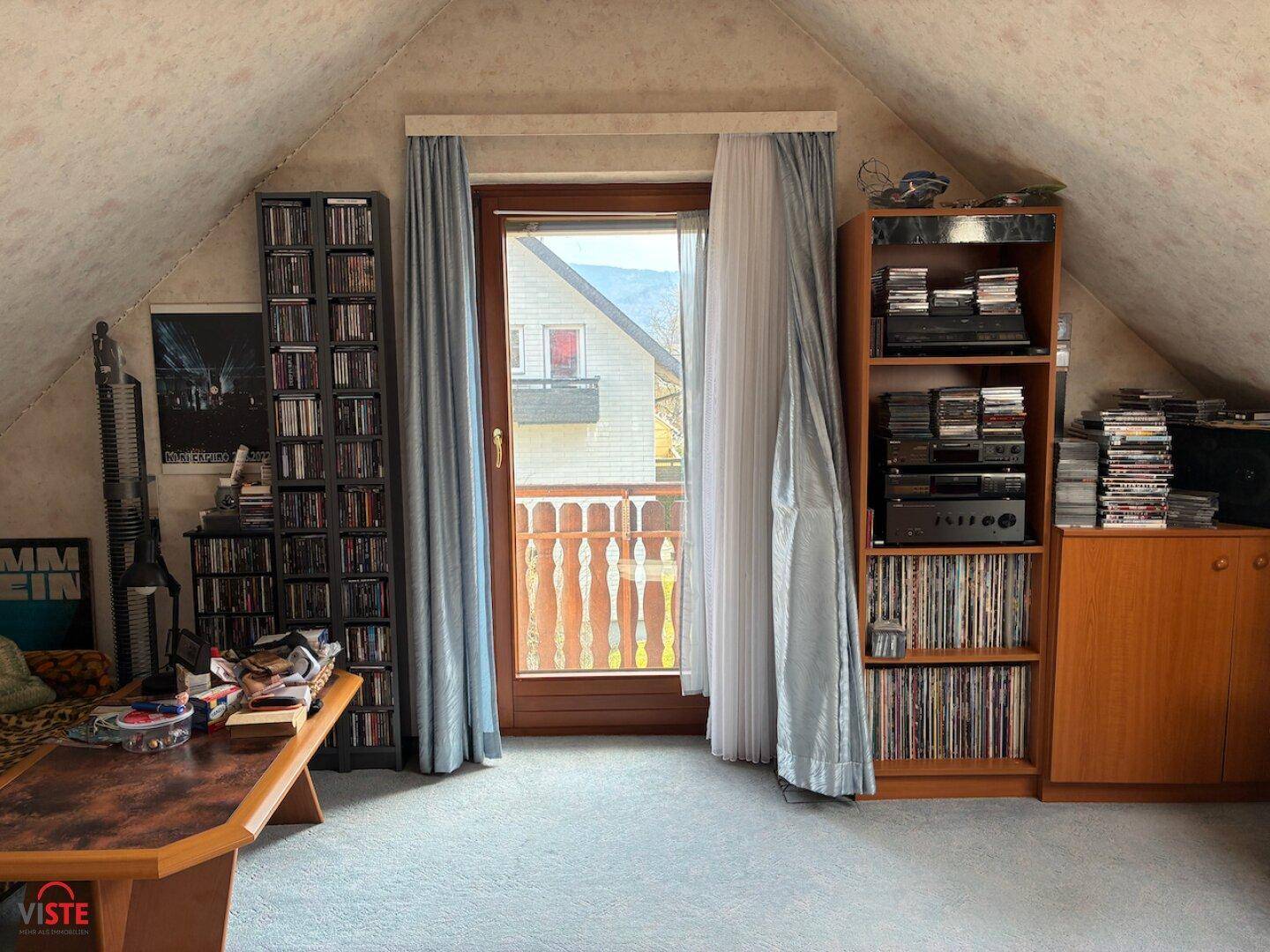 Dachgeschosszimmer mit Teppichboden, Schrägen und Zugang zu einem französischen Balkon.