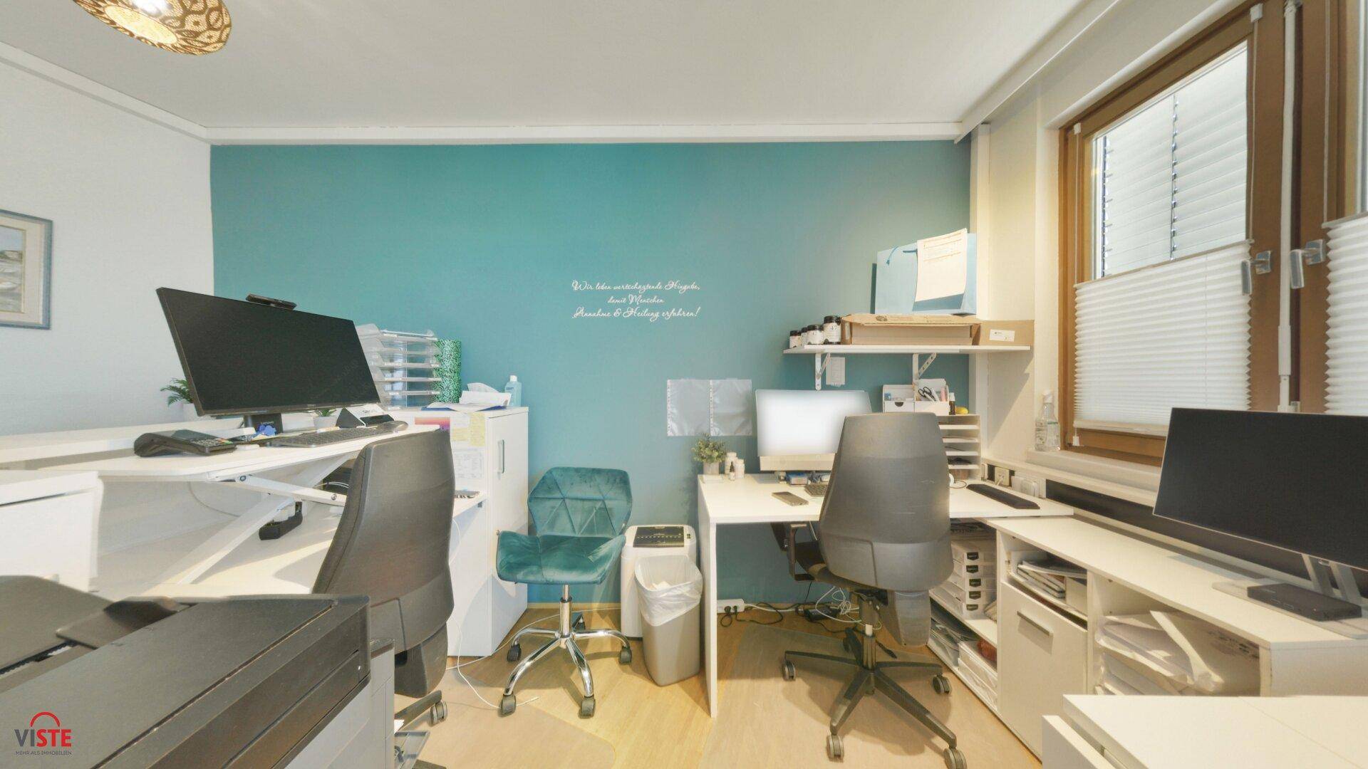 Modernes Büro mit mehreren Arbeitsplätzen, Computern und einer auffälligen türkisen Akzentwand.