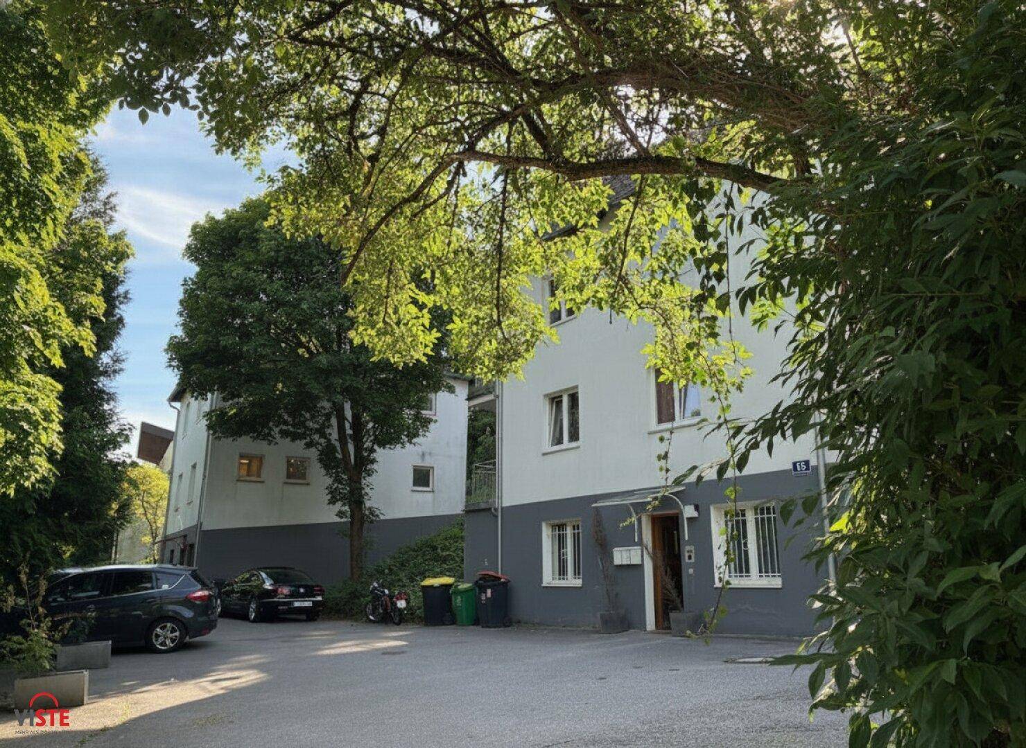 Außenansicht des Gebäudes umgeben von Bäumen und Parkplätzen bei Sonnenlicht.