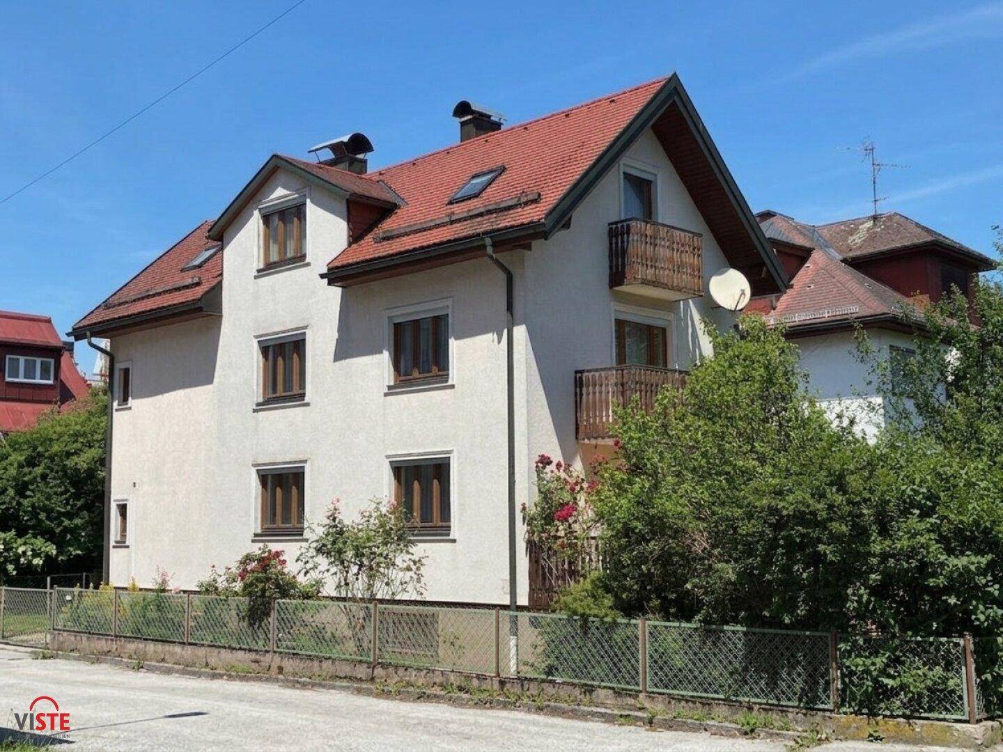Seitenansicht des Wohnhauses mit rotem Ziegeldach, Gaubenfenstern und gepflegtem Gartenbereich.