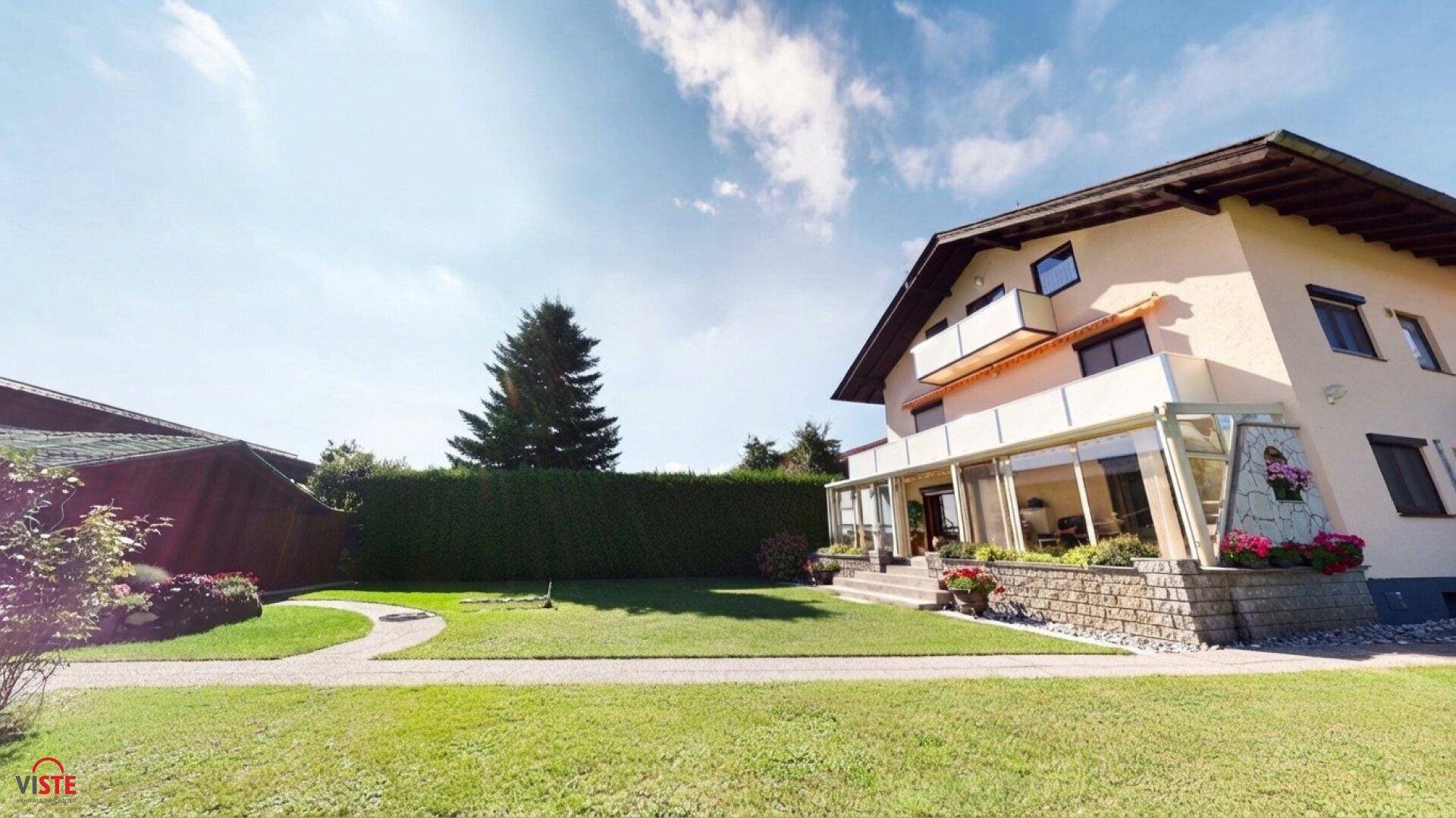 Weitläufiger Garten mit grüner Rasenfläche und Blick auf die Hausfassade.