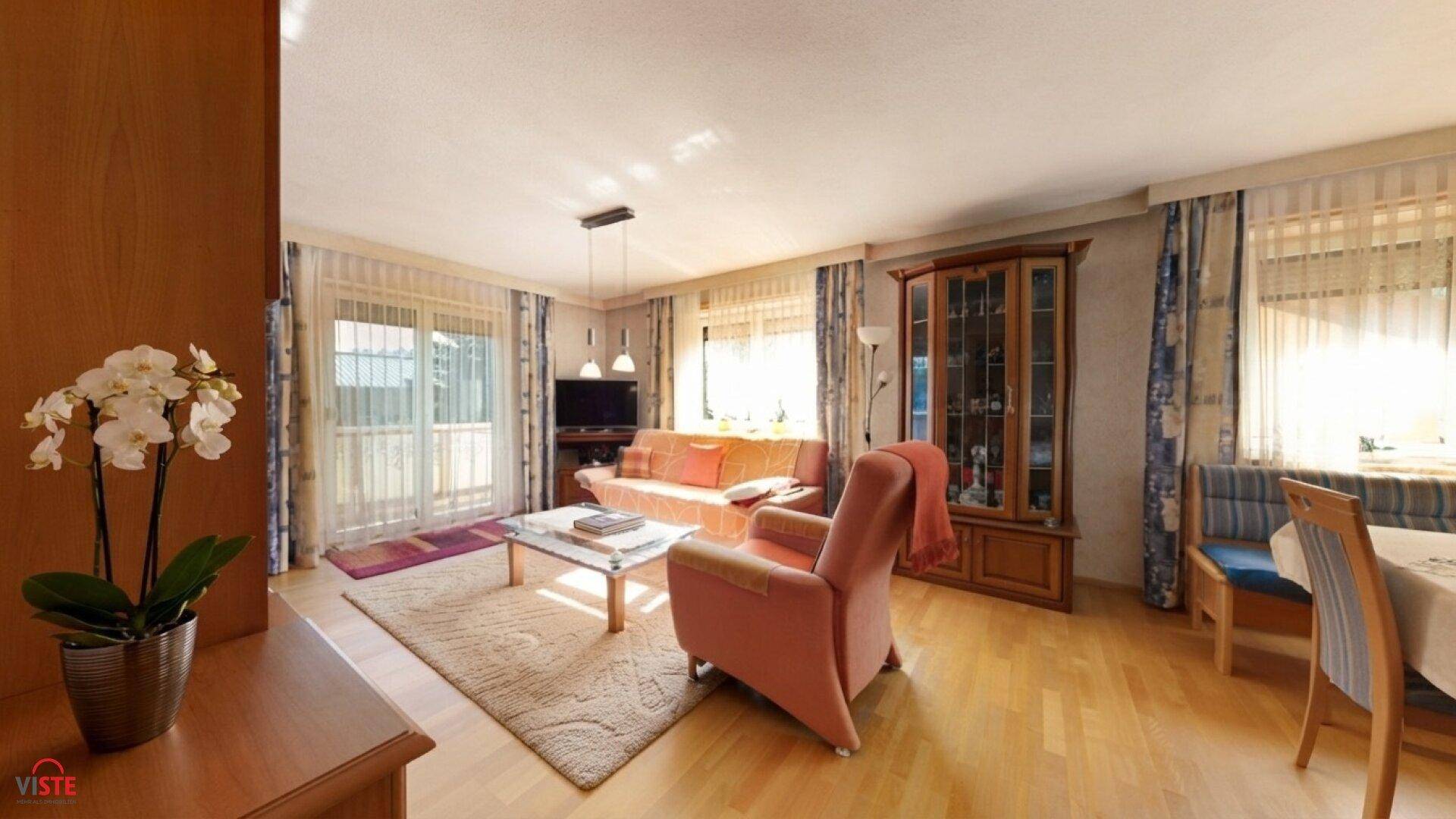 Heller Wohn- und Essbereich mit Parkettboden, gemütlichen Möbeln und Zugang zum Balkon.