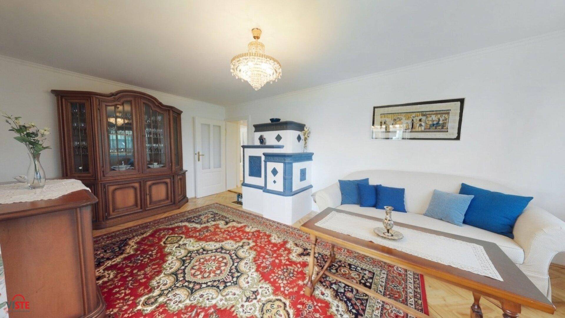 Gemütliches Wohnzimmer mit traditionellem Kachelofen, Holzboden und orientalischem Teppich.