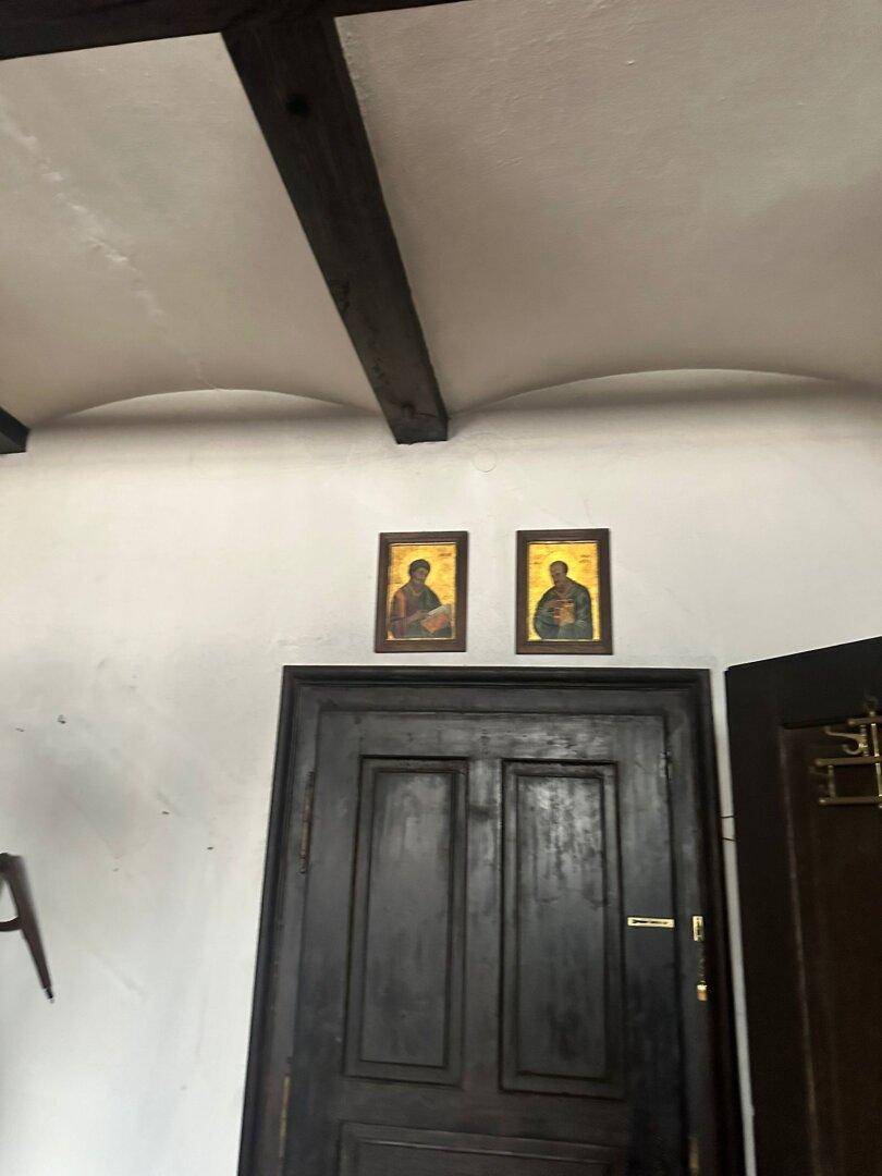 Innenraum mit gewölbter Decke, sichtbaren Holzbalken und einer dunklen Holztür.