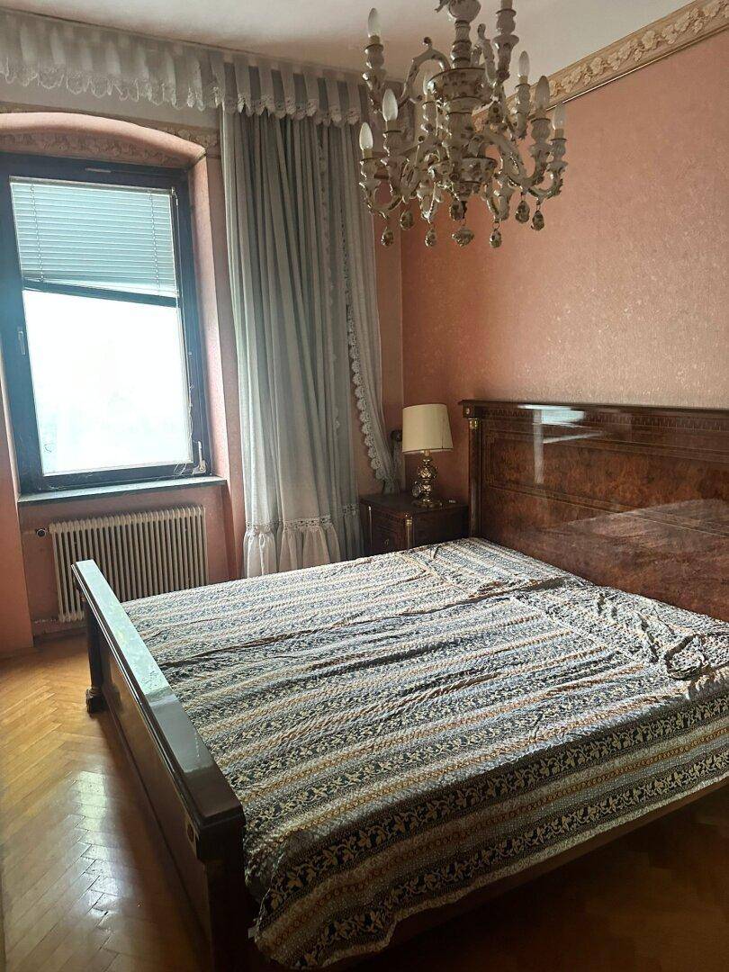 Schlafzimmer mit Doppelbett, klassischem Mobiliar, rosa Wänden und Kronleuchter.
