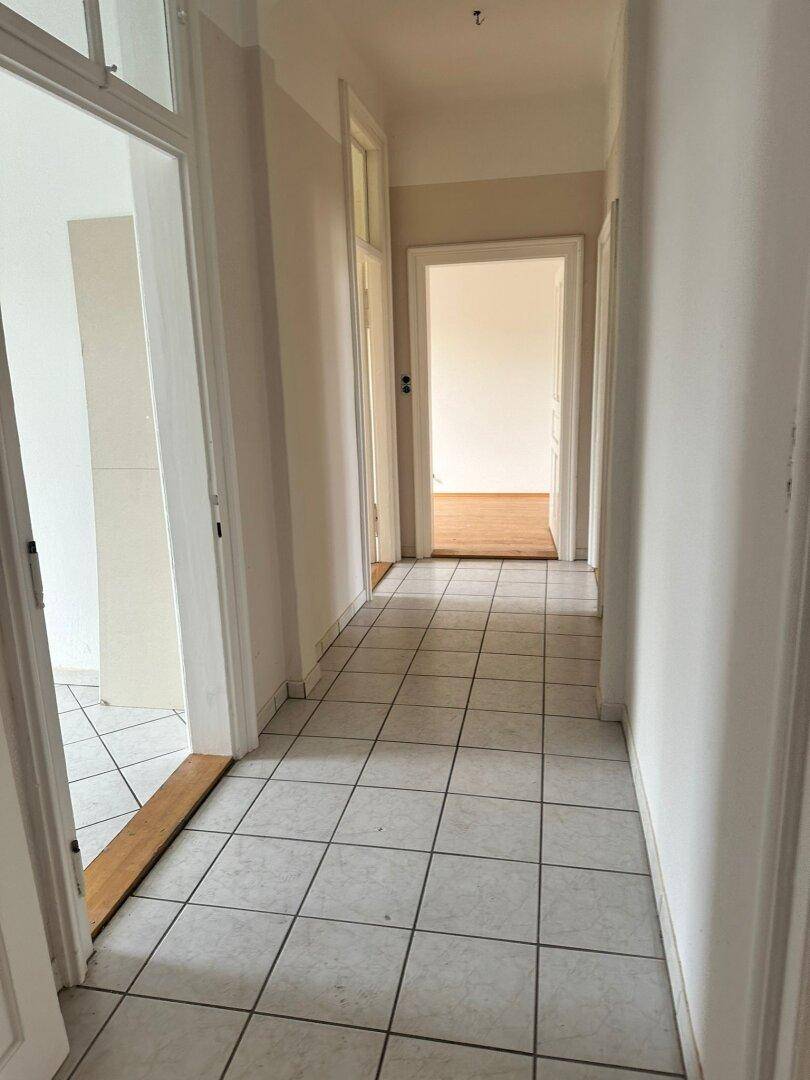 Heller Flur mit Fliesenboden und mehreren Türen zu angrenzenden Räumen.