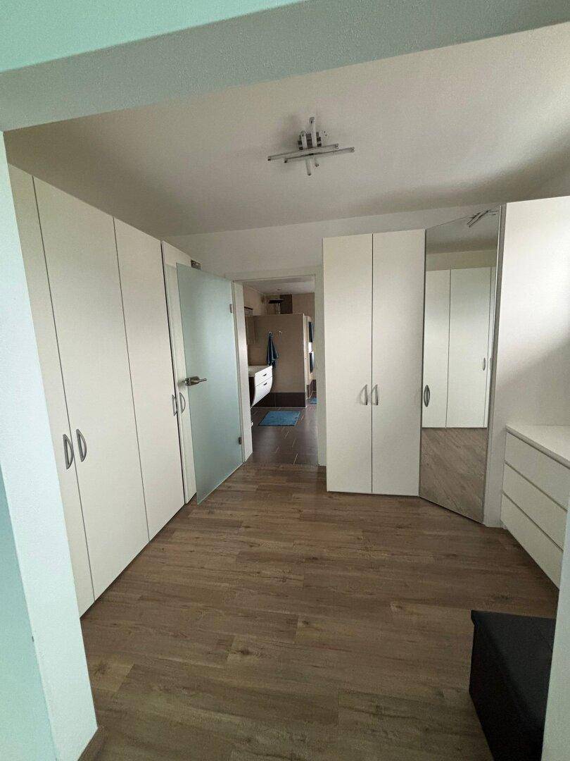 Heller Flur mit Einbauschränken, Holzfußboden und Zugang zu weiteren Räumen.