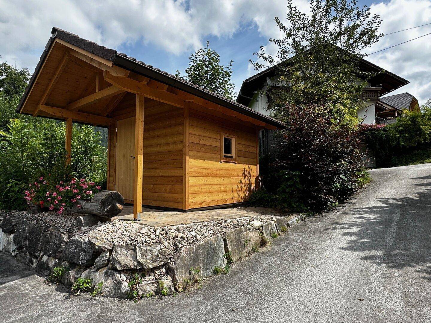 Kleines, charmantes Holzhaus im Garten, möglicherweise als Geräteschuppen oder Sauna nutzbar.