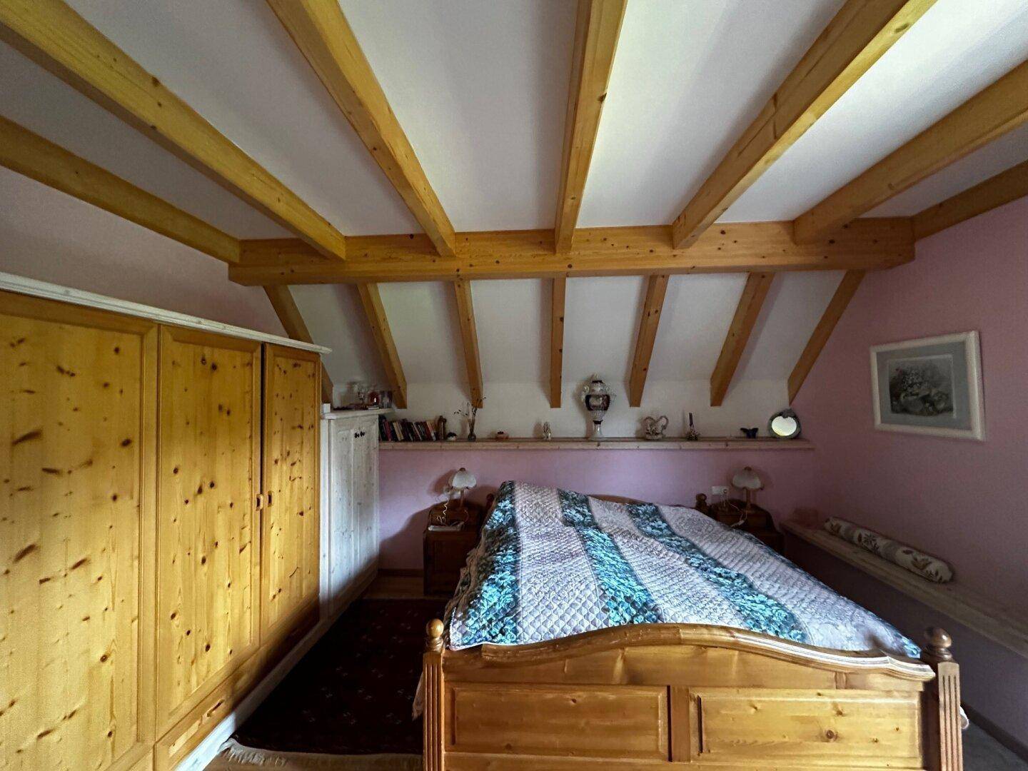 Geräumiges Schlafzimmer mit Holzbalkendecke, Holzschrank und traditionellem Bett, mit Holzboden.