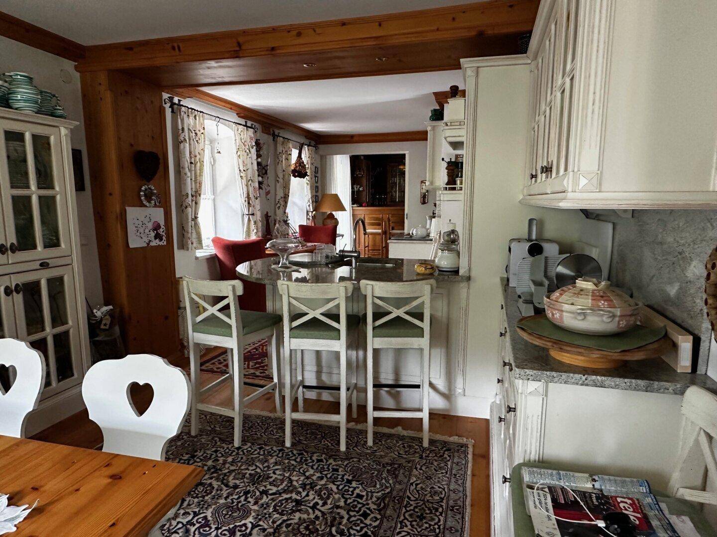 Traditionelle Küche mit Frühstücksbar, weißen Schränken und Blick in den Essbereich, mit Holzboden.