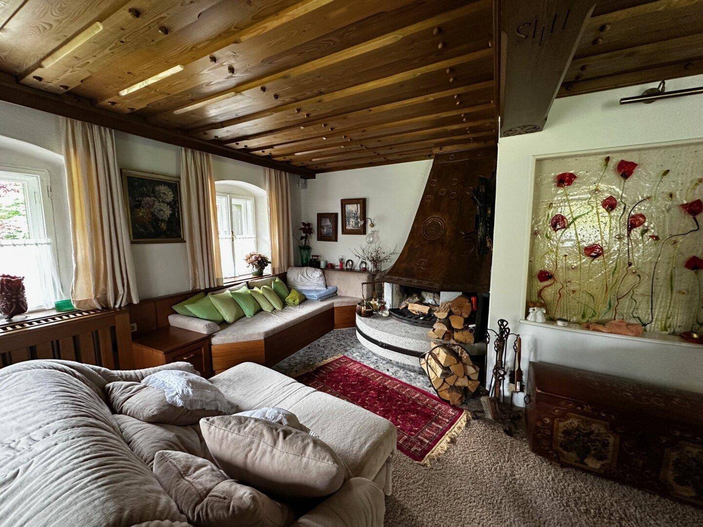 Geräumiges Wohnzimmer mit großem Kamin, Holzbalkendecke und bequemen Sofas, im alpinen Stil.