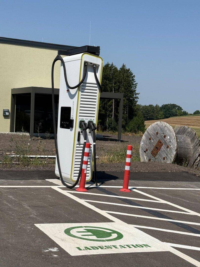Moderne Ladestation für Elektrofahrzeuge auf einem Parkplatz, deutlich gekennzeichnet mit Bodenmarkierung.