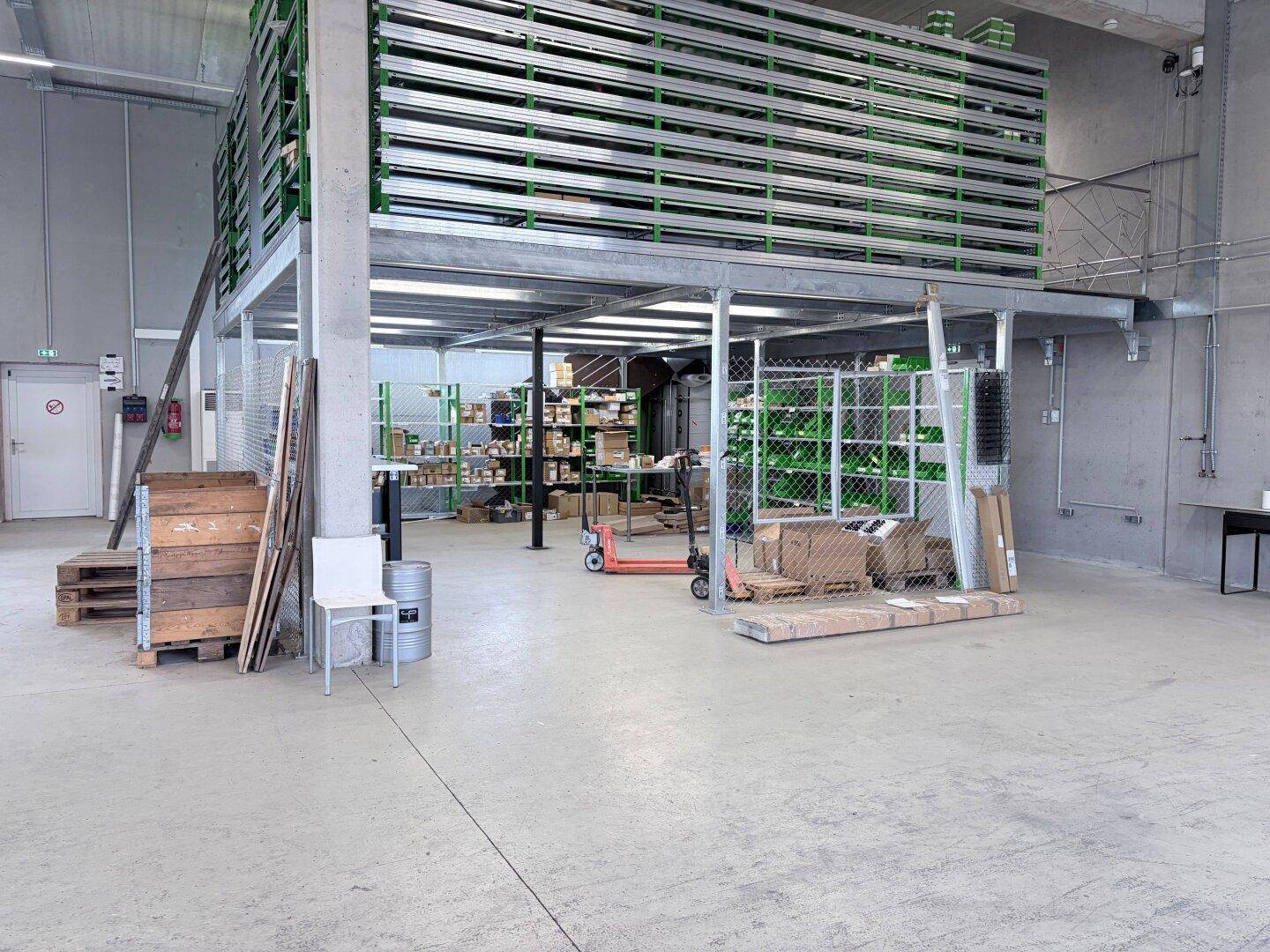 Eine weitere Ansicht des zweistöckigen Regalsystems in der Lagerhalle mit Paletten und einem Hubwagen.