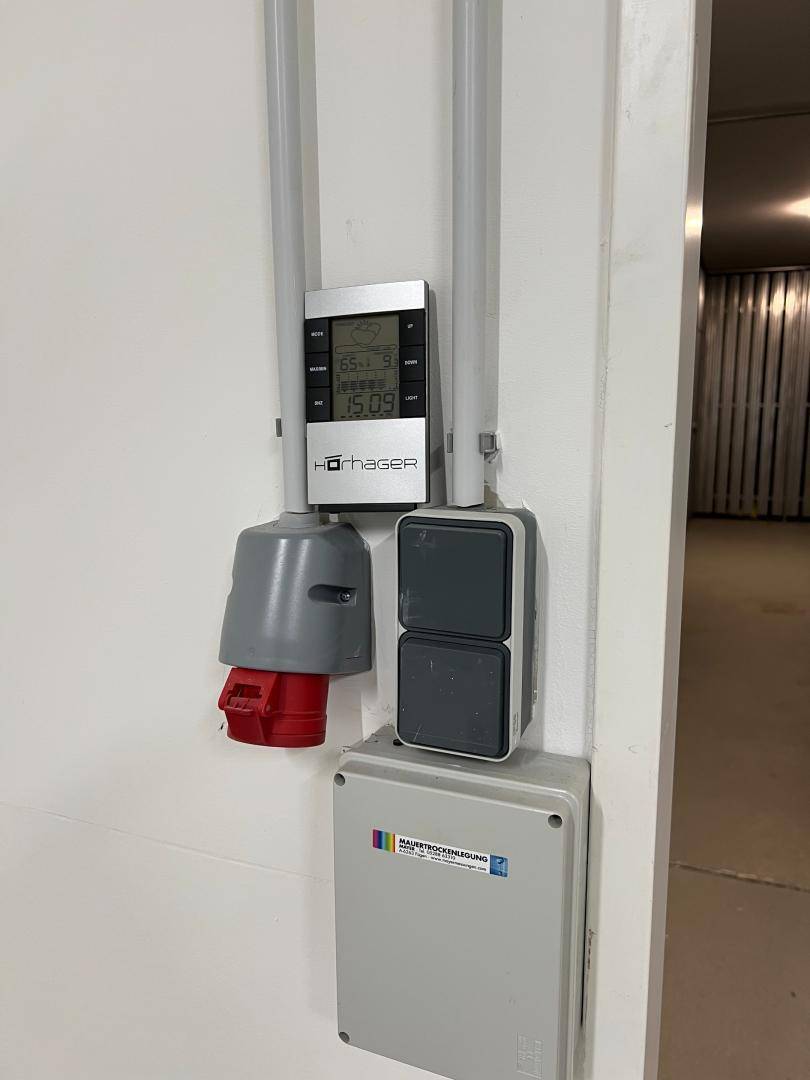 Nahaufnahme einer Wand mit elektrischen Installationen, Steckdosen und einem digitalen Bedienfeld.