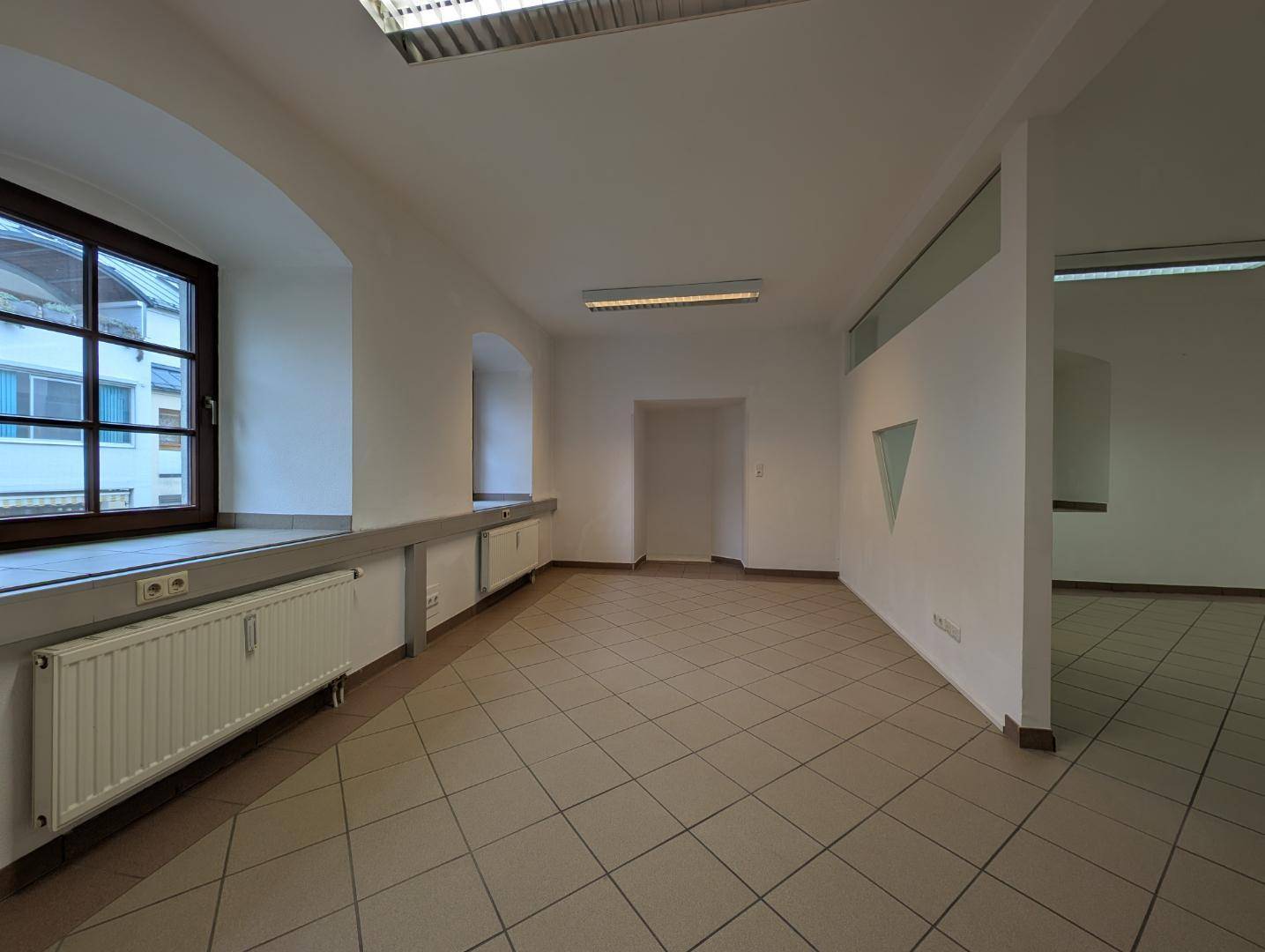 Heller Gewerberaum mit großen Fenstern und Fliesenboden, bietet flexible Gestaltungsmöglichkeiten für verschiedene Nutzungen.