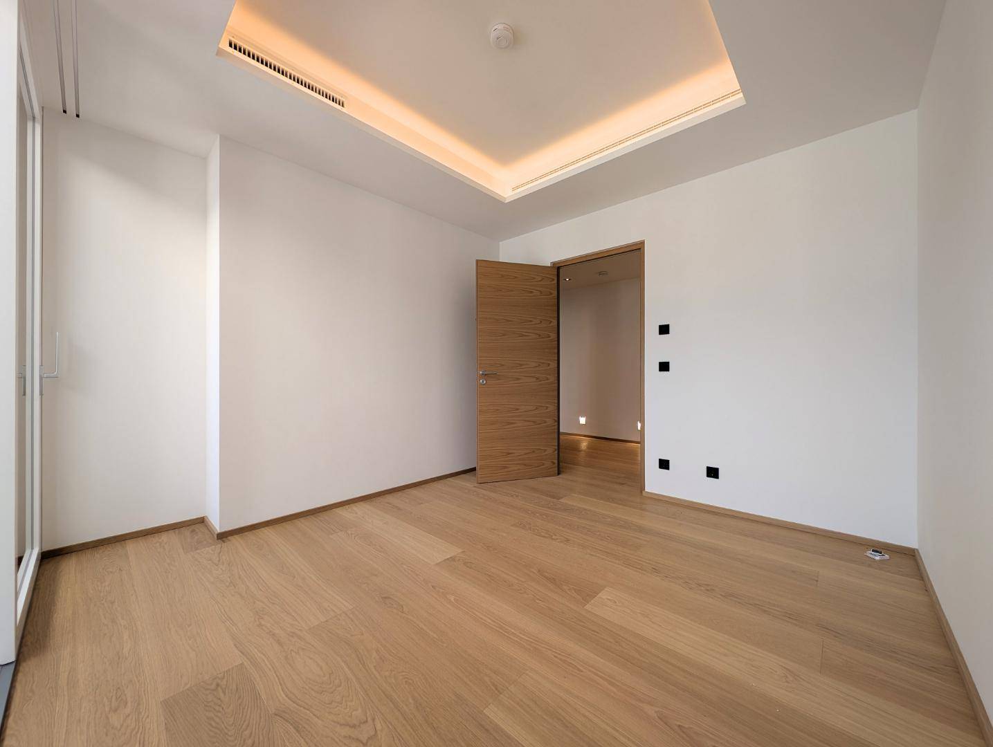 Helles Schlafzimmer mit Holzboden und moderner Deckenbeleuchtung.