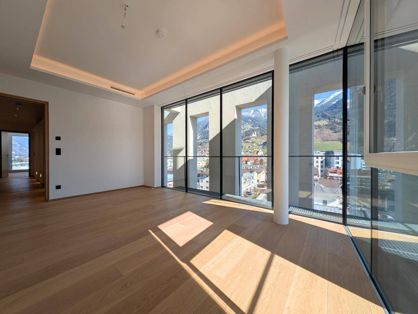 Heller Wohnraum mit Holzboden, großen Fenstern und Bergblick.