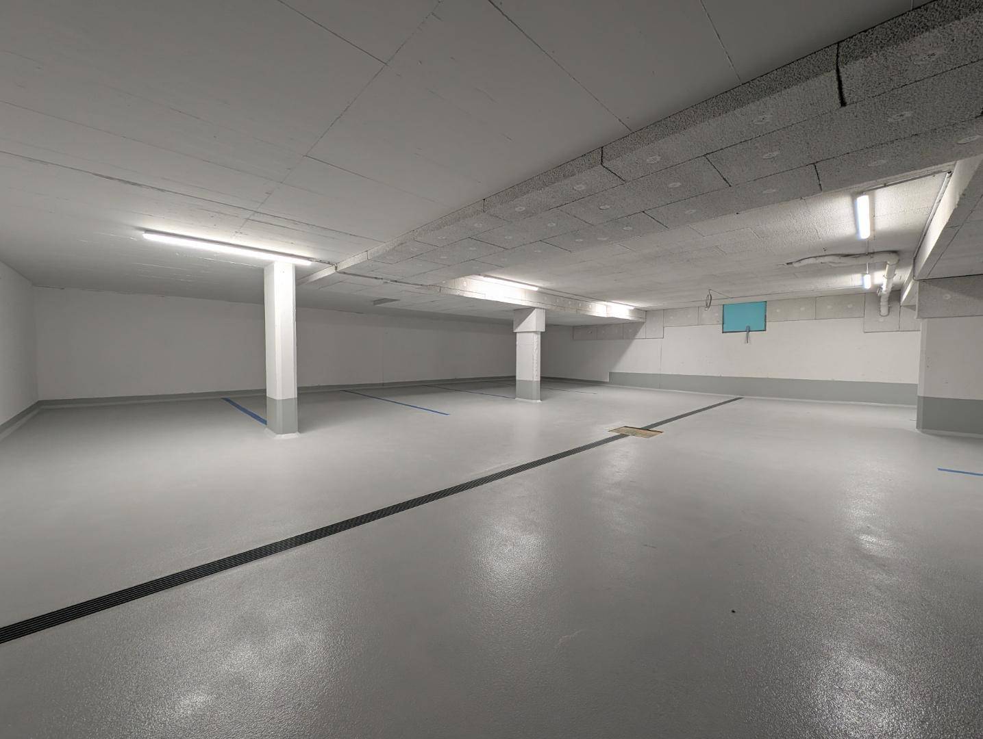 Geräumige und saubere Tiefgarage eines Neubaus mit markierten Stellplätzen.