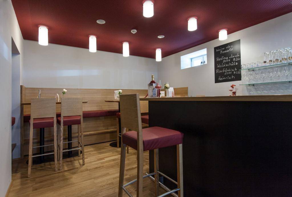 Gemütlicher Barbereich mit Holzboden, roter Decke und modernen Barhockern, ideal für gesellige Abende.