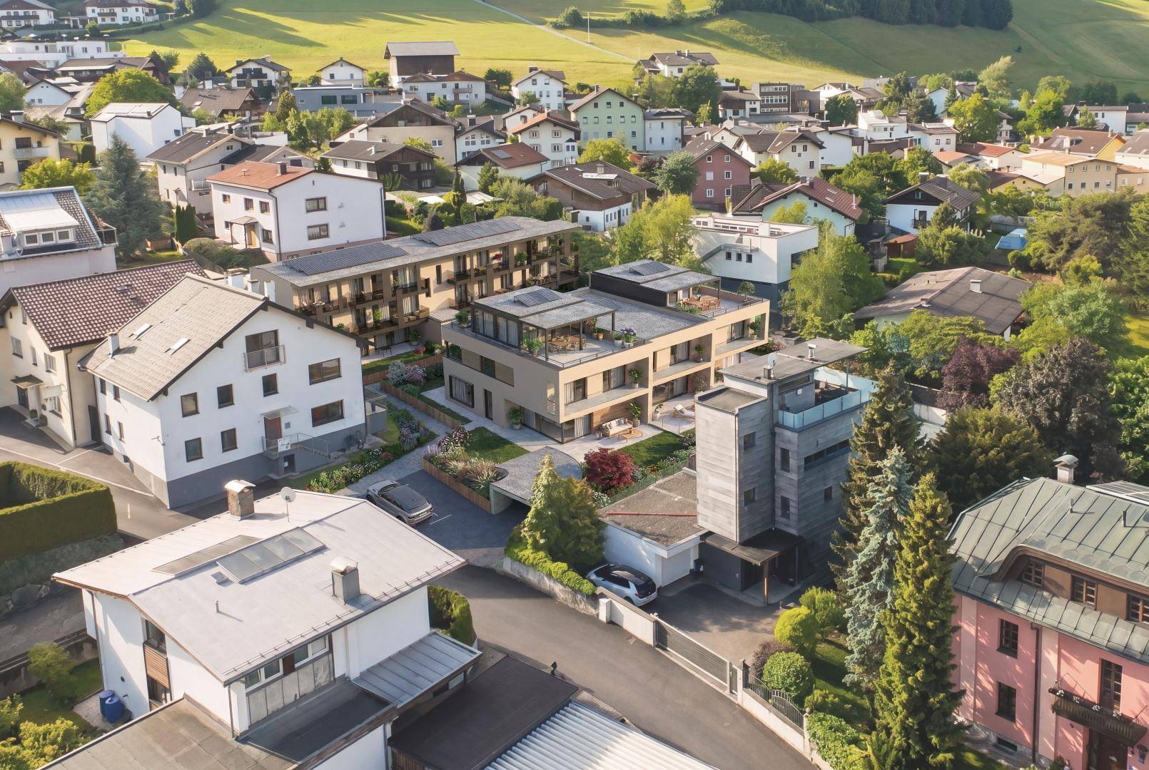 Luftaufnahme einer modernen Wohnanlage eingebettet in eine grüne Wohnsiedlung mit Bergblick.