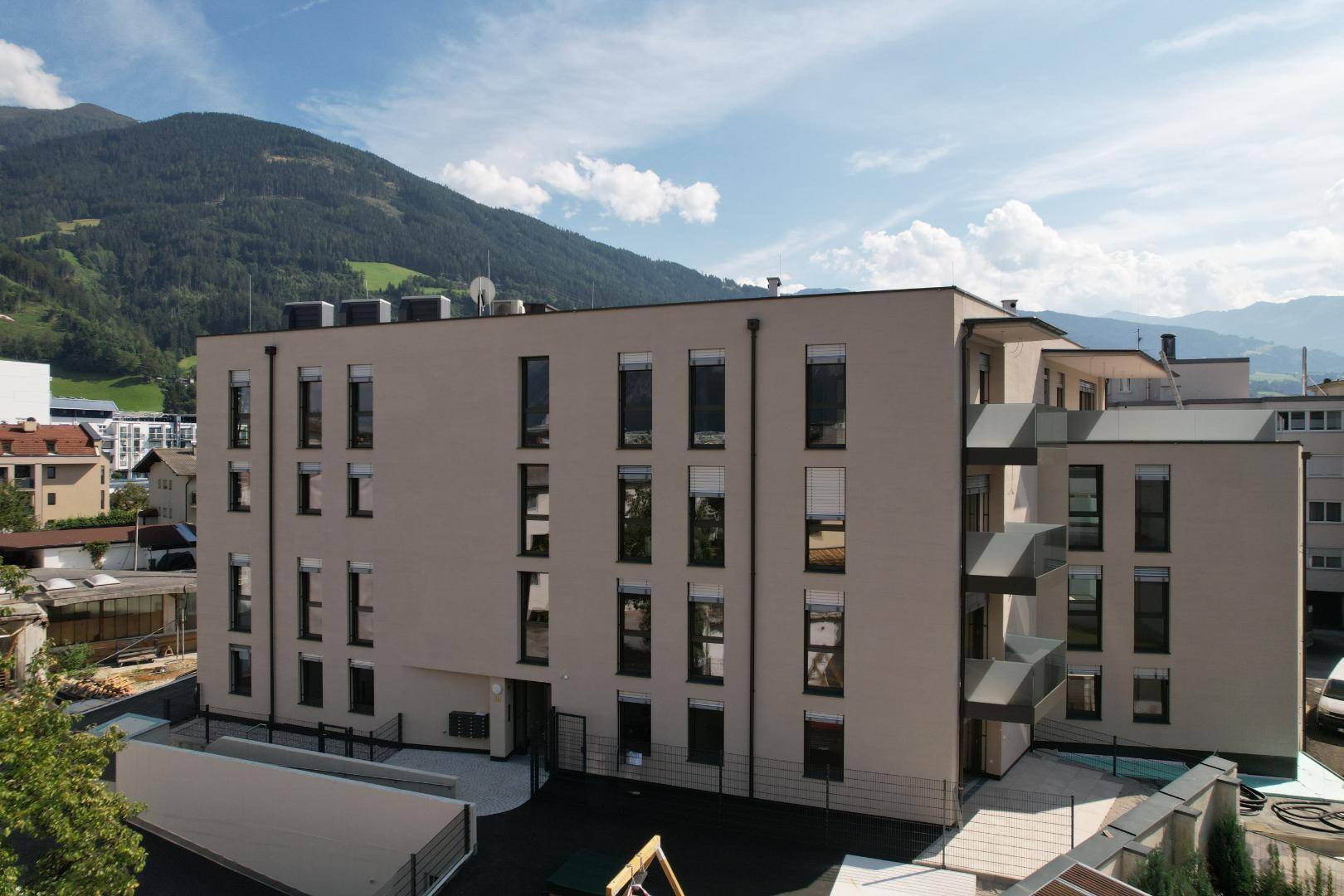 Rückansicht des modernen Wohngebäudes mit zahlreichen Fenstern und Bergblick.