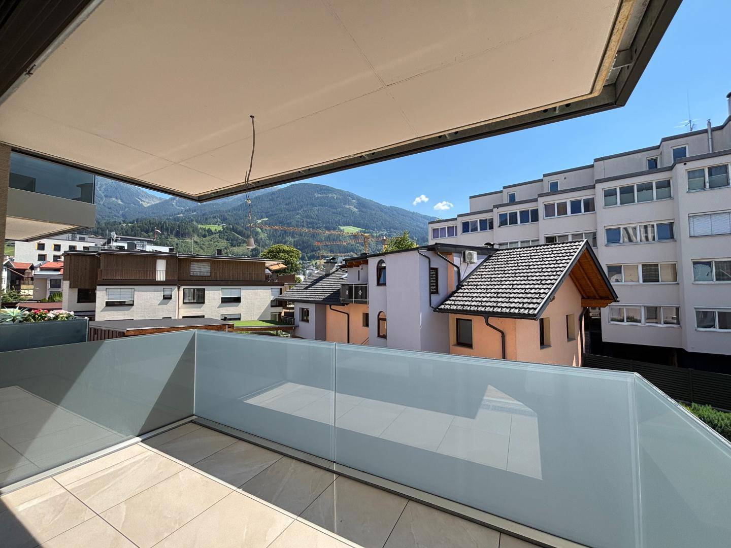 Geräumiger Balkon mit Glasgeländer und weitem Blick auf die umliegende Berglandschaft.