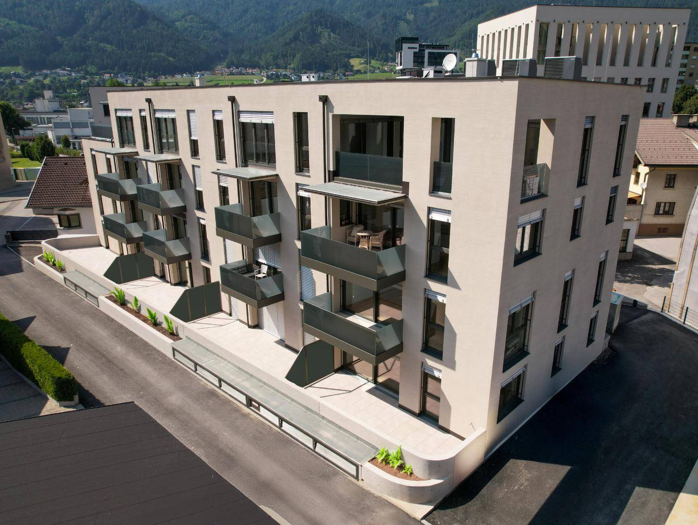 Modernes Mehrfamilienhaus mit Balkonen und einer ansprechenden Fassade vor Bergkulisse.