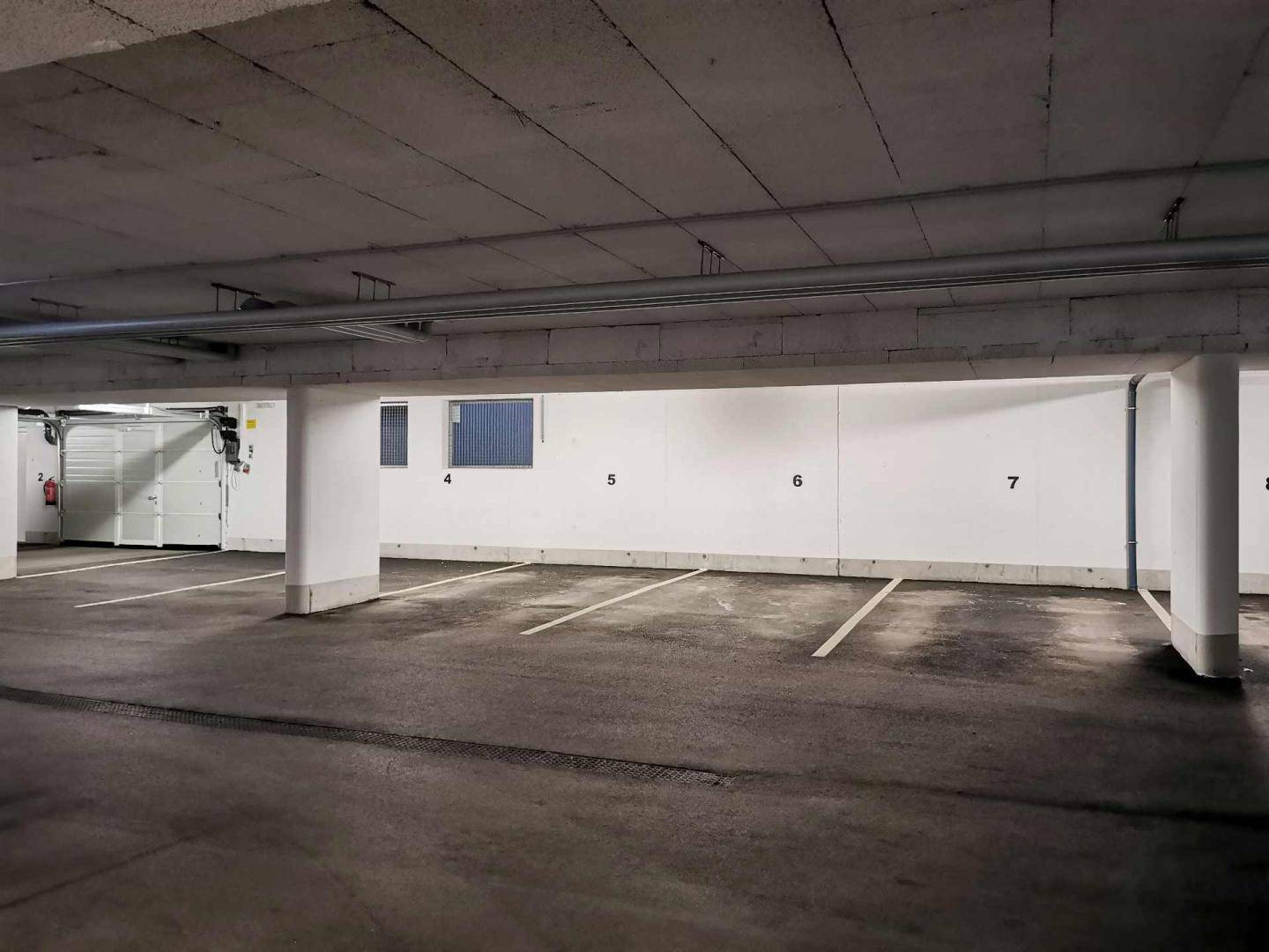 Geräumige Tiefgarage mit hellen Wänden und mehreren freien Parkplätzen.