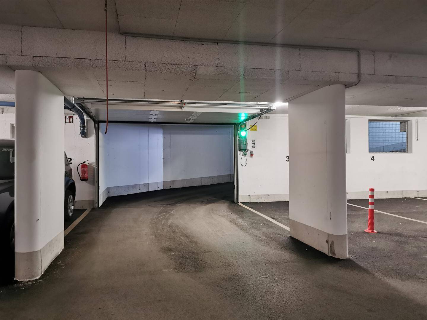 Einfahrt zur Tiefgarage mit Ampelsystem, breiter Zufahrtsrampe und sauberer Umgebung.