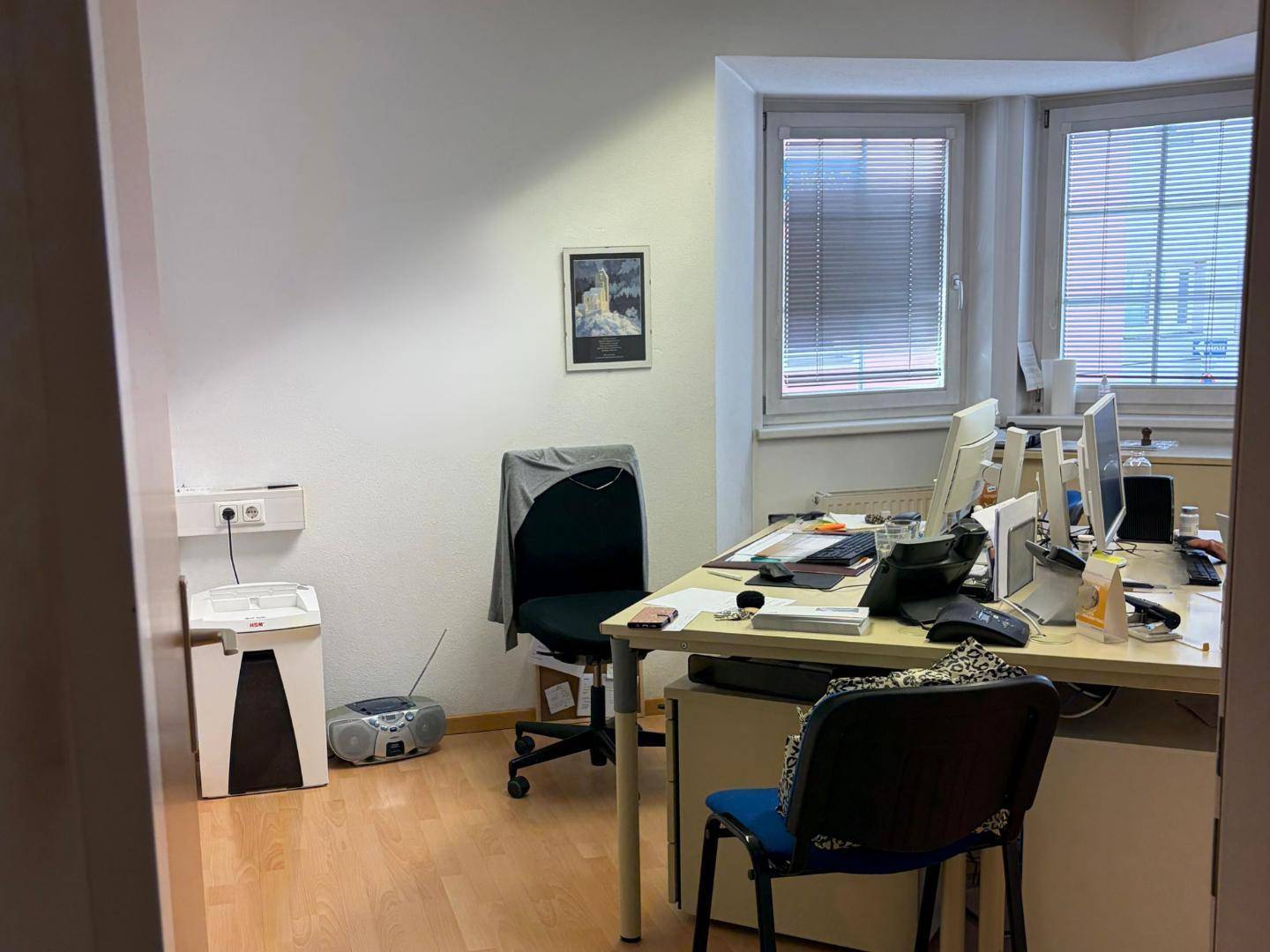 Büroraum mit mehreren Arbeitsplätzen, Fenstern und Jalousien für Privatsphäre.