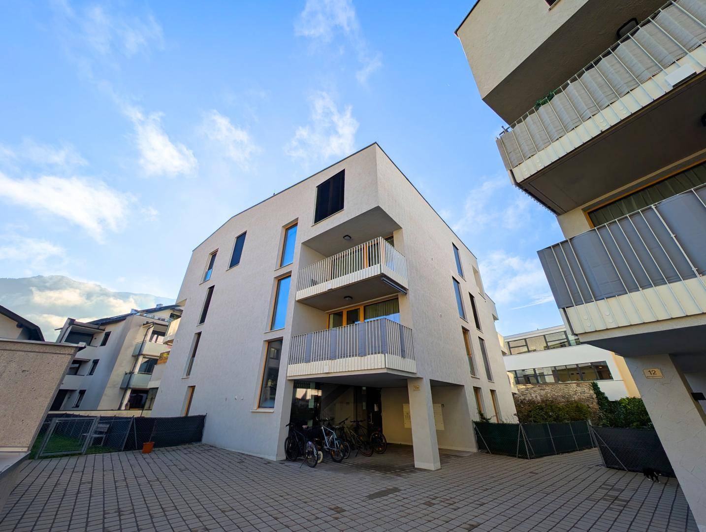 Moderne Wohnanlage mit heller Fassade, Balkonen und Fahrradabstellplätzen im Freien.